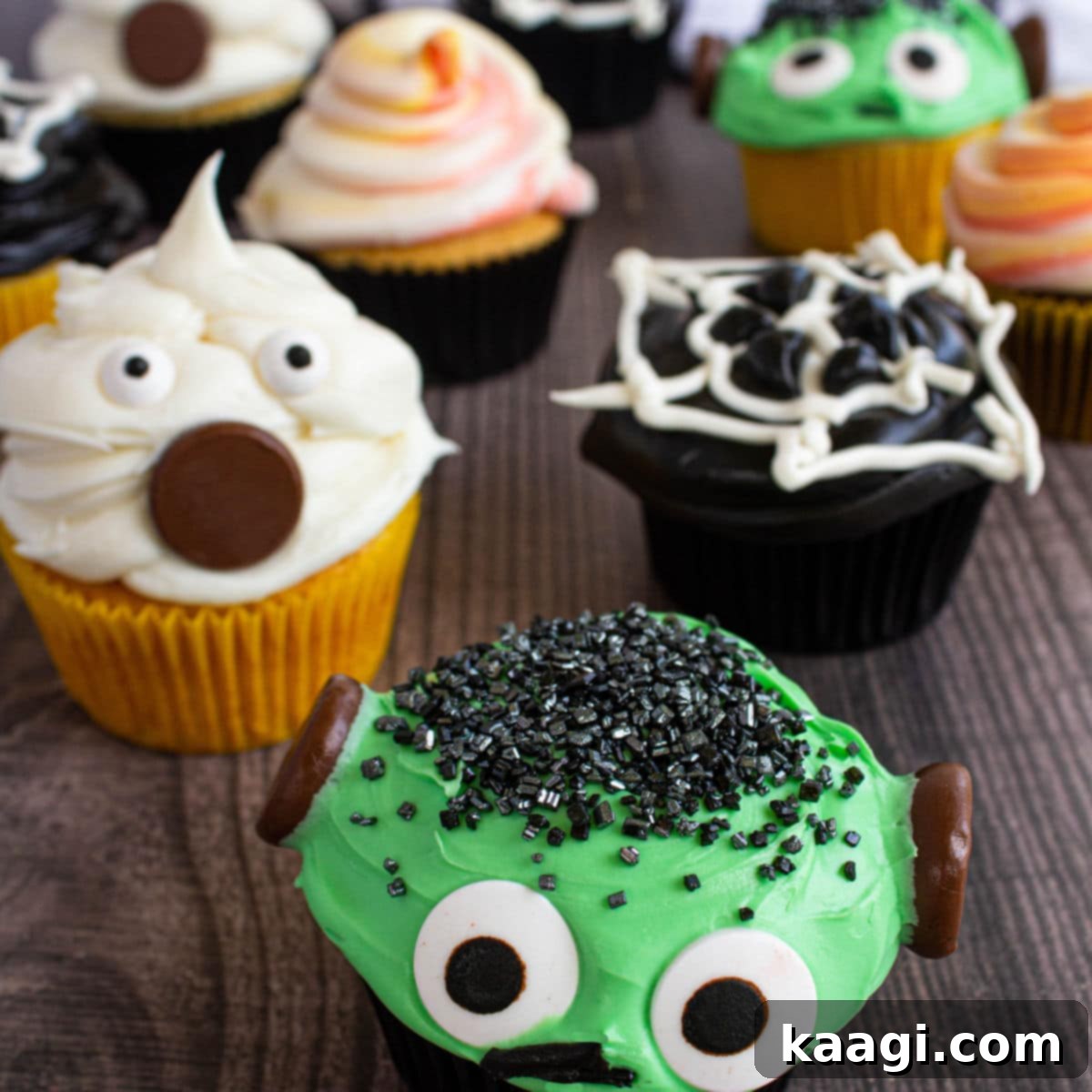 Close up of various Halloween cupcakes, including ghost, Frankenstein, and spiderweb designs.