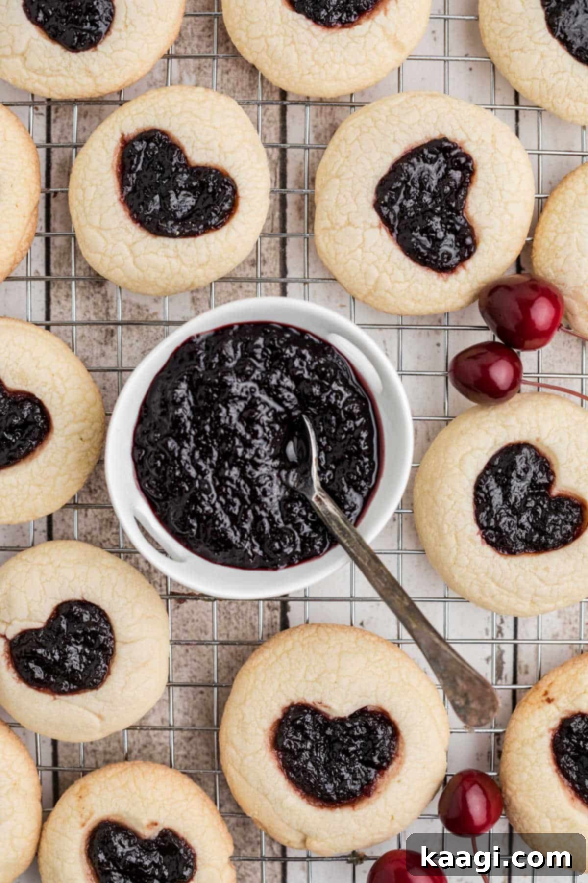 Viral Jam Heart Cookies 5 A delightful arrangement of Jam Heart Cookies encircling a small bowl filled with rich, homemade Cherry Jam.