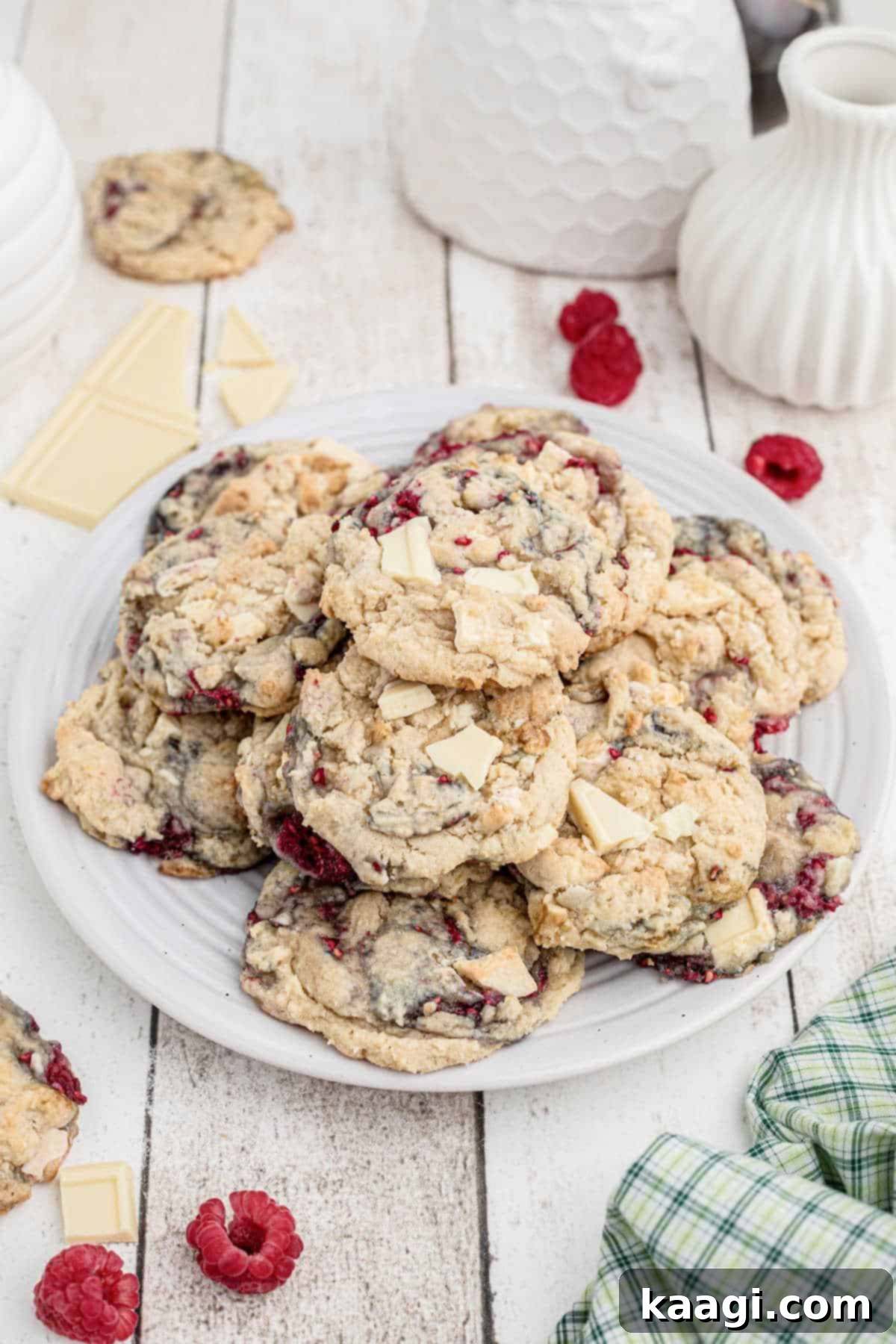 Side view of a plate full of irresistible white chocolate raspberry cookies, showcasing their chewy texture and vibrant fruit.