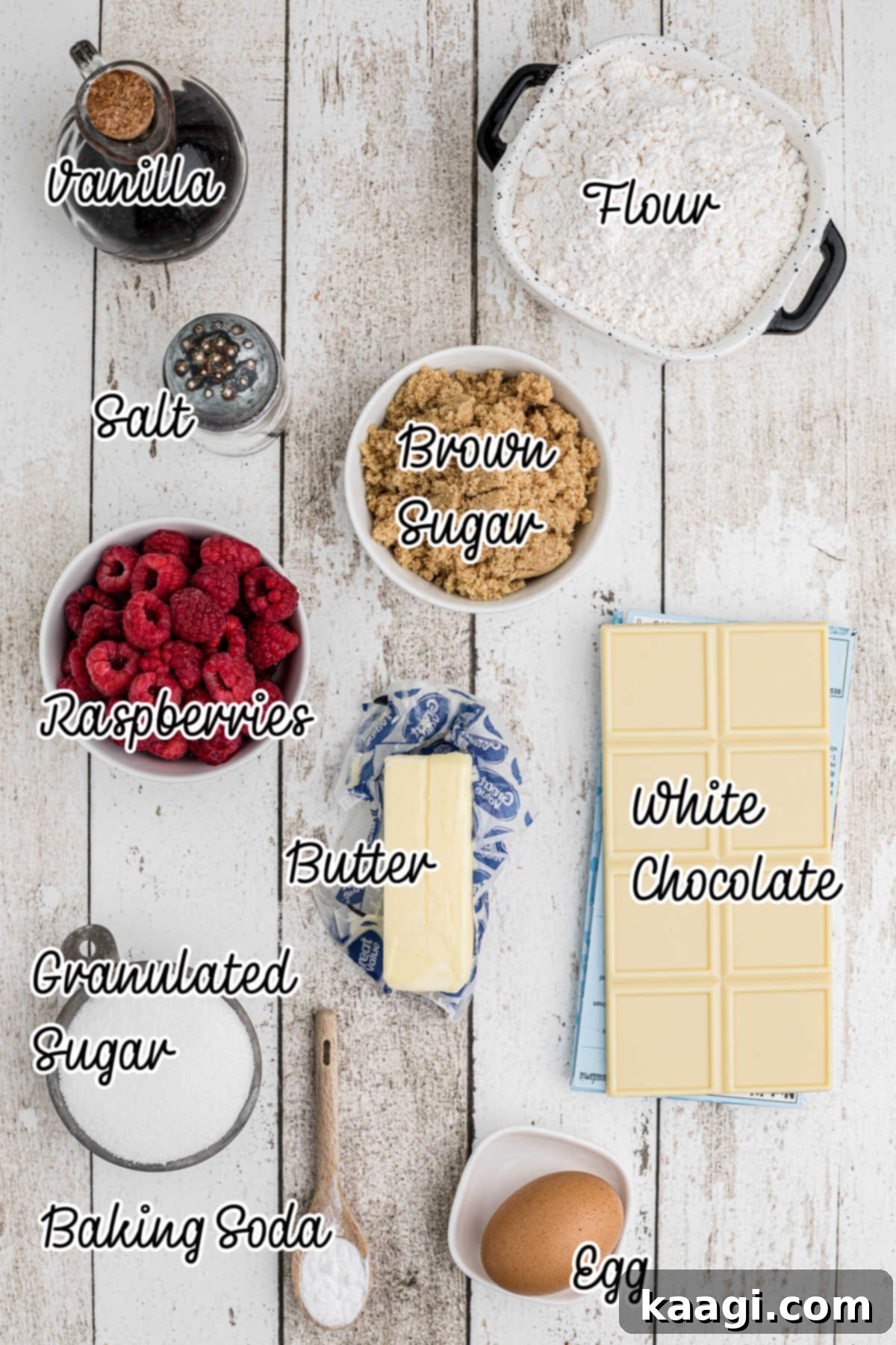 A carefully arranged flat lay of all the fresh ingredients needed to make white chocolate raspberry cookies, including butter, sugars, flour, and ripe raspberries.
