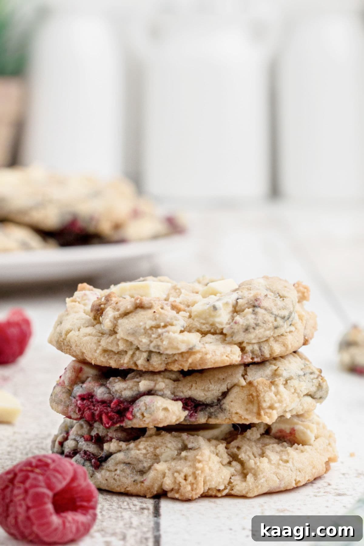 A side view of a stack of fluffy and chewy white chocolate raspberry cookies, highlighting their texture and generous fillings.