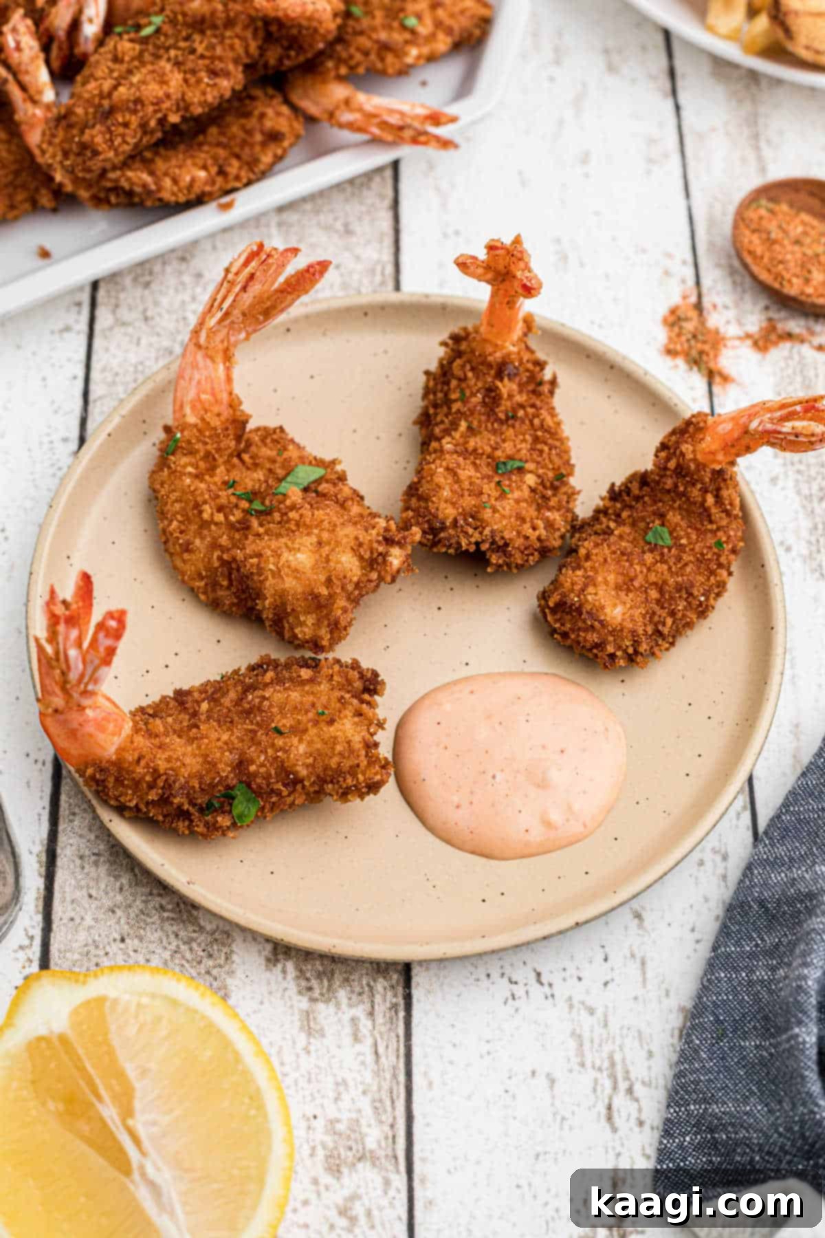 Close up of a plate of delicious butterfly shrimp surrounding a small bowl of dipping sauce.