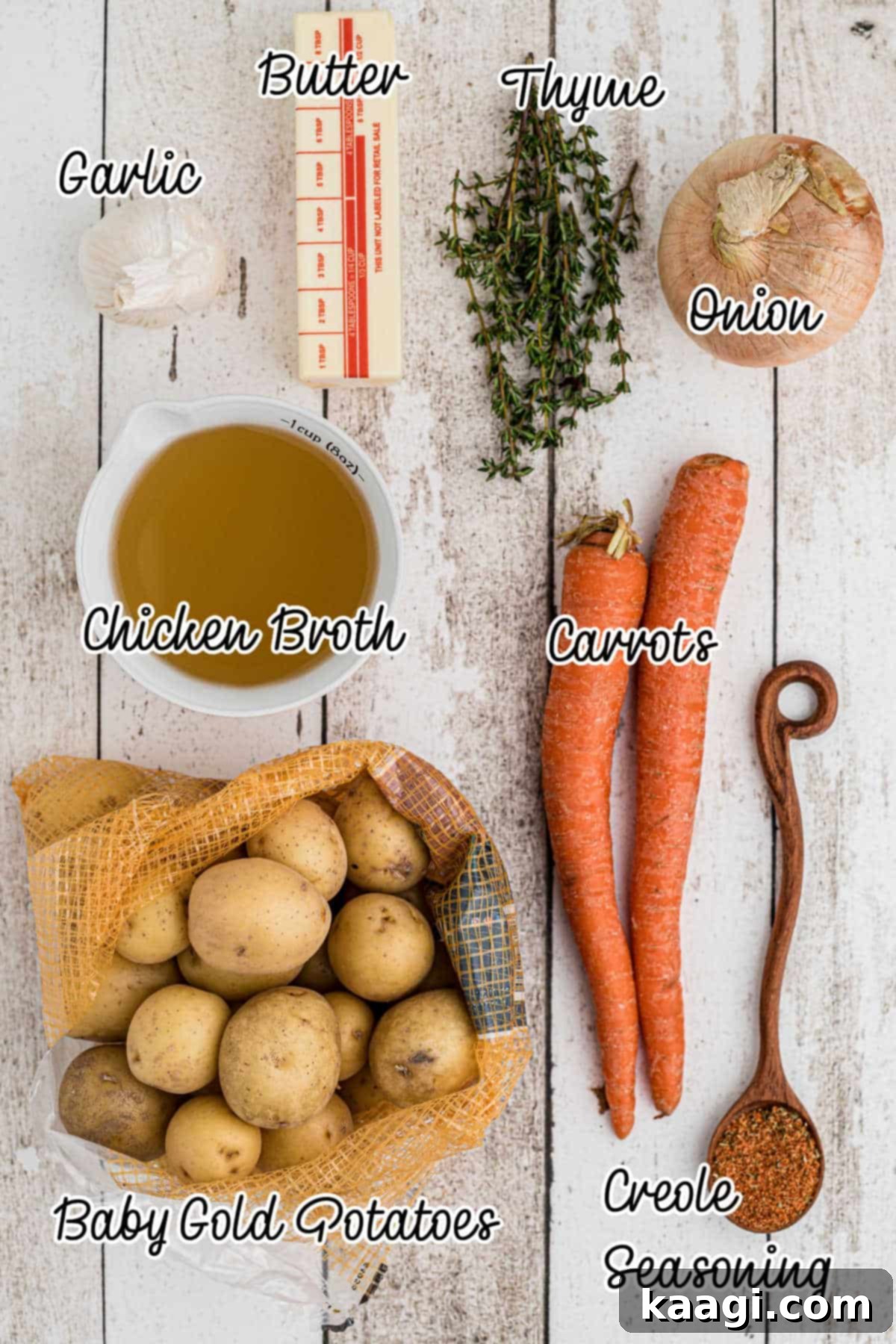 A flat lay photograph showcasing all the fresh ingredients needed for Instant Pot Potatoes and Carrots: baby gold potatoes, carrots, onion, garlic, butter, fresh thyme, and Creole seasoning.