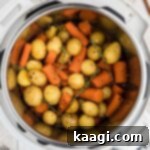 Close up overhead of an instant pot with potatoes and carrots, showing the vibrant color and texture.