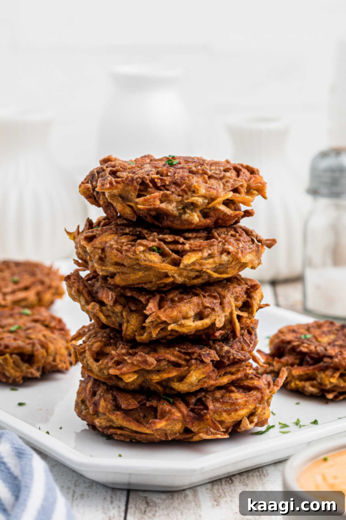 Side shot of a stack of golden-brown sweet potato fritters on a plate, highlighting their crispy texture and delicious appearance.