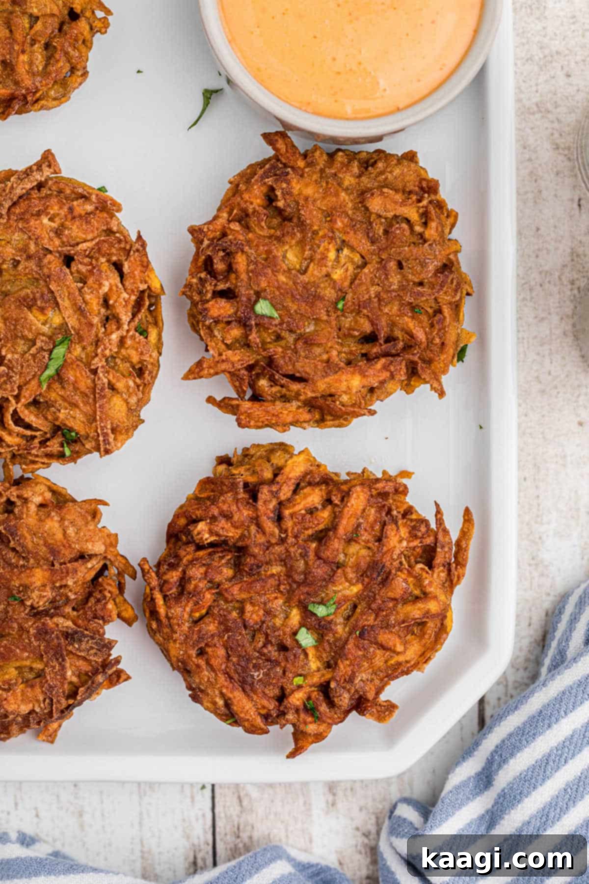 Overhead close up shot of a plate of sweet potato fritters with a dip, showing the vibrant colors and tempting texture of the dish.