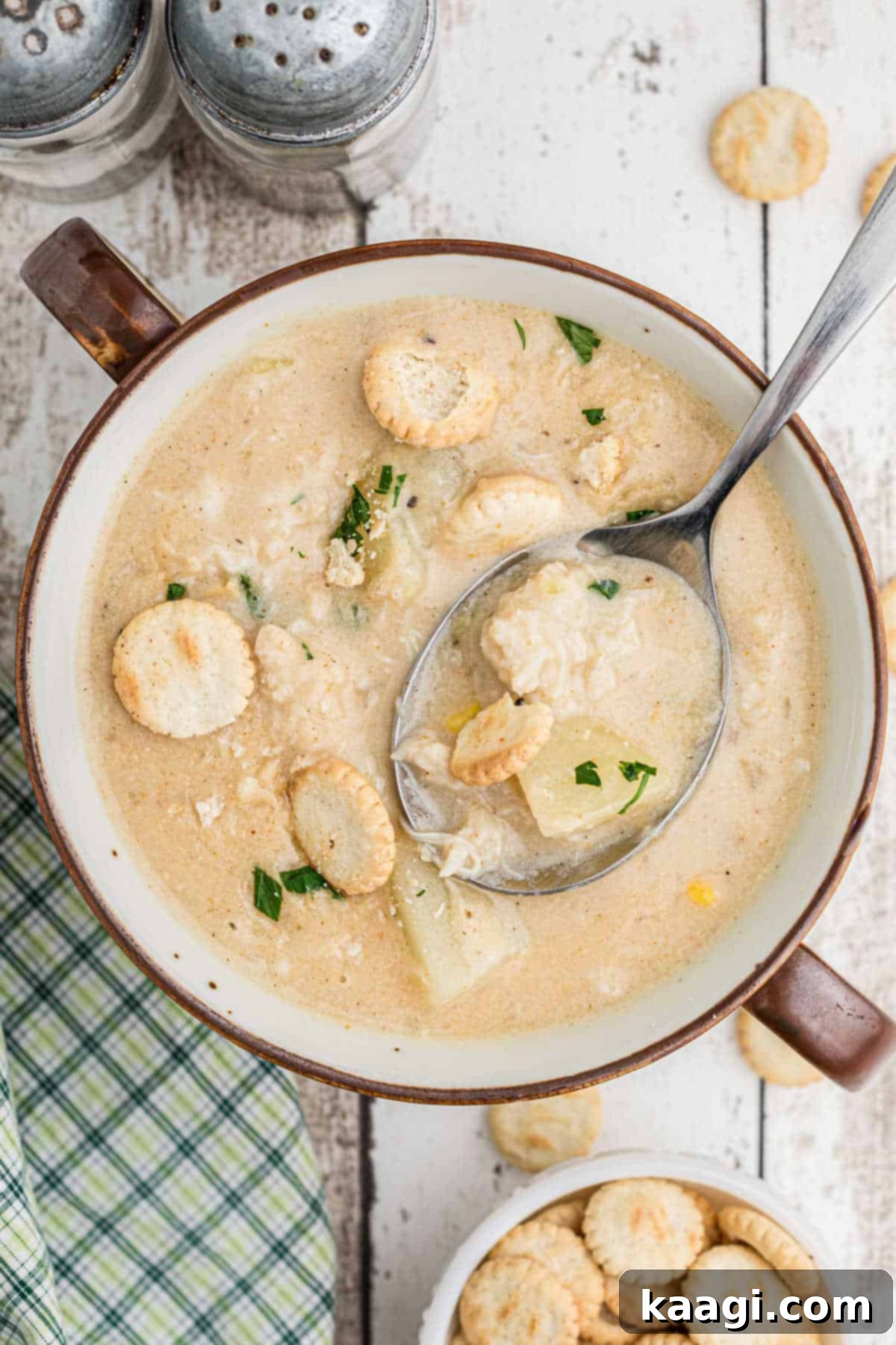 A vibrant bowl of creamy crab chowder, with a spoon revealing chunks of crab and potatoes.