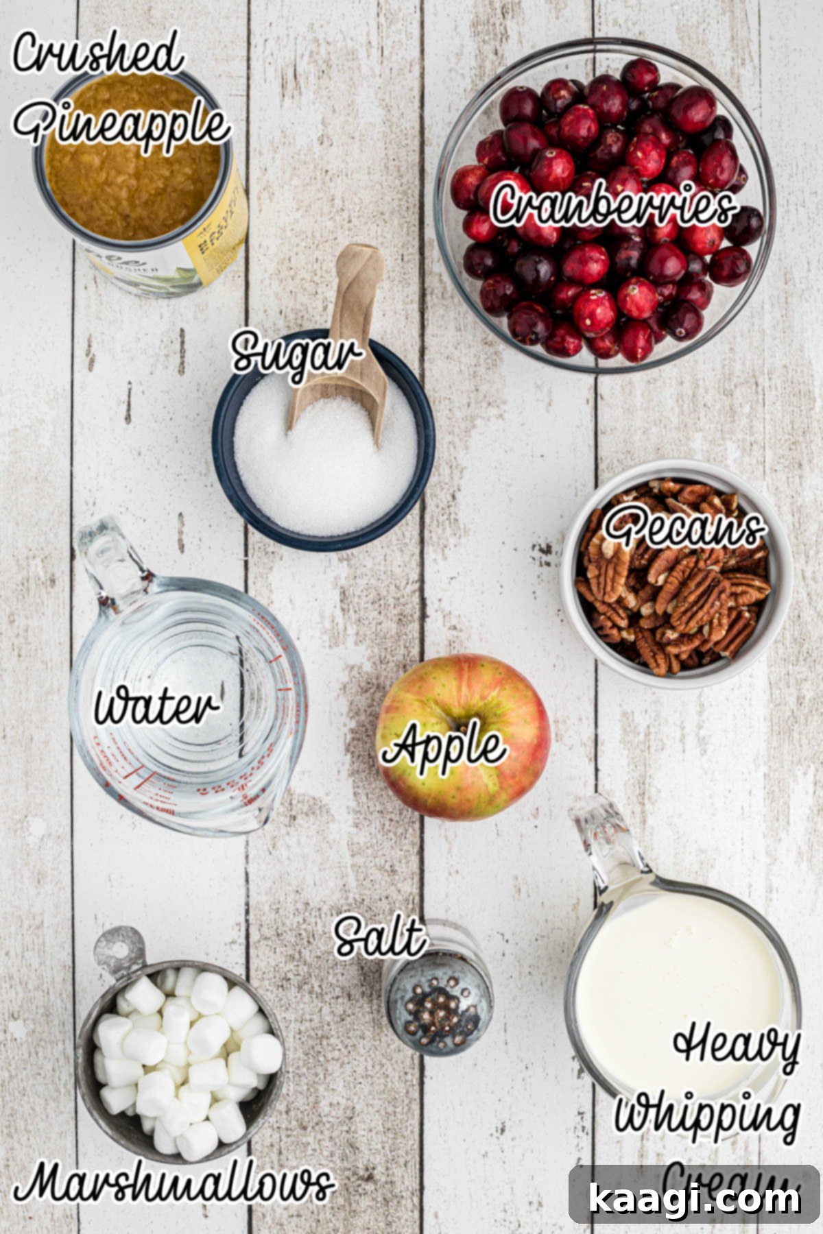 Overhead image of ingredients needed to make a cranberry salad, including cranberries, marshmallows, pecans, apples, and cream.