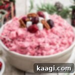 A cropped square image of a bowl of cranberry salad with some cranberries and marshmallows on top.