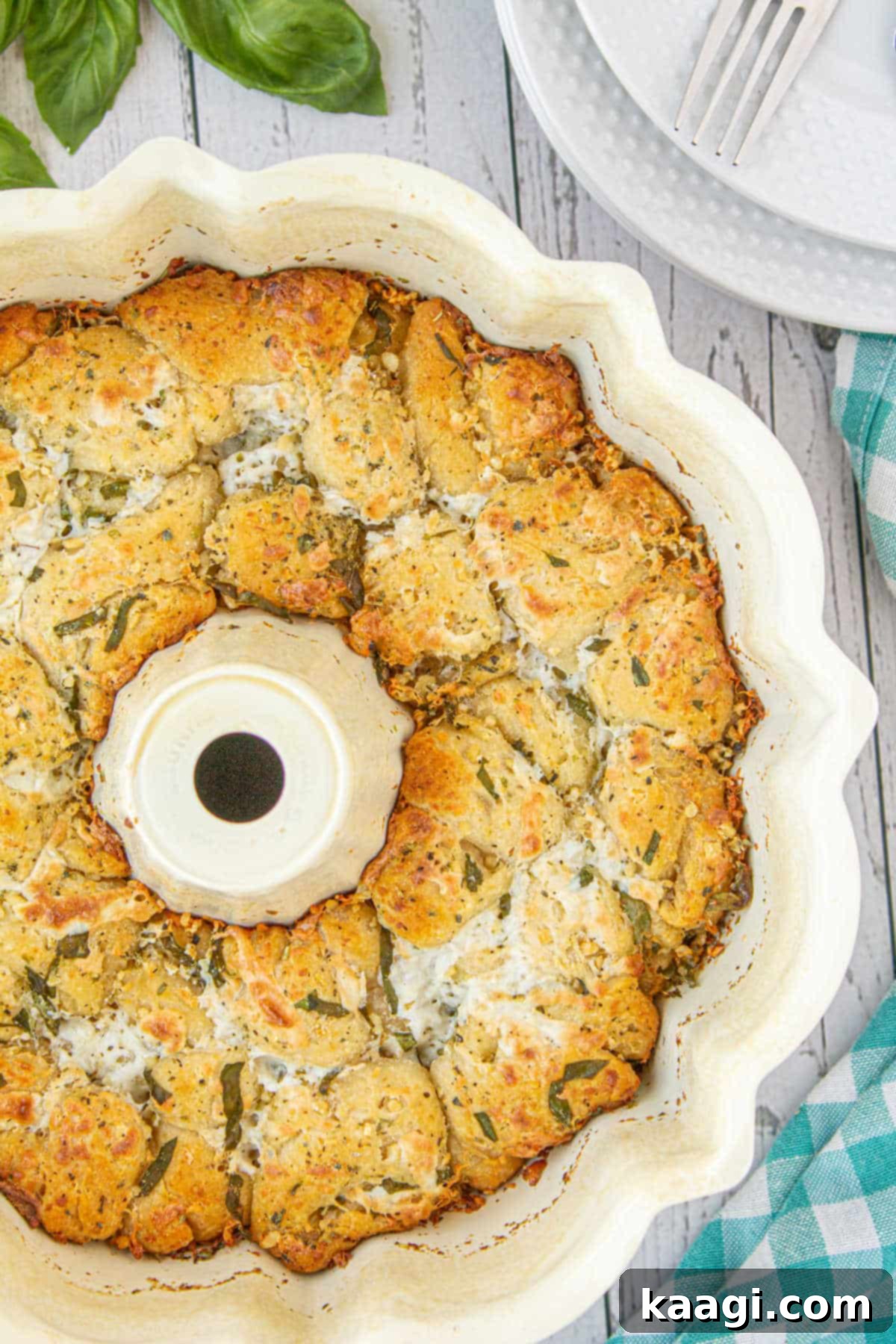 Overhead close up view of an Italian Monkey bread in a bundt pan, golden brown and garnished with fresh herbs.