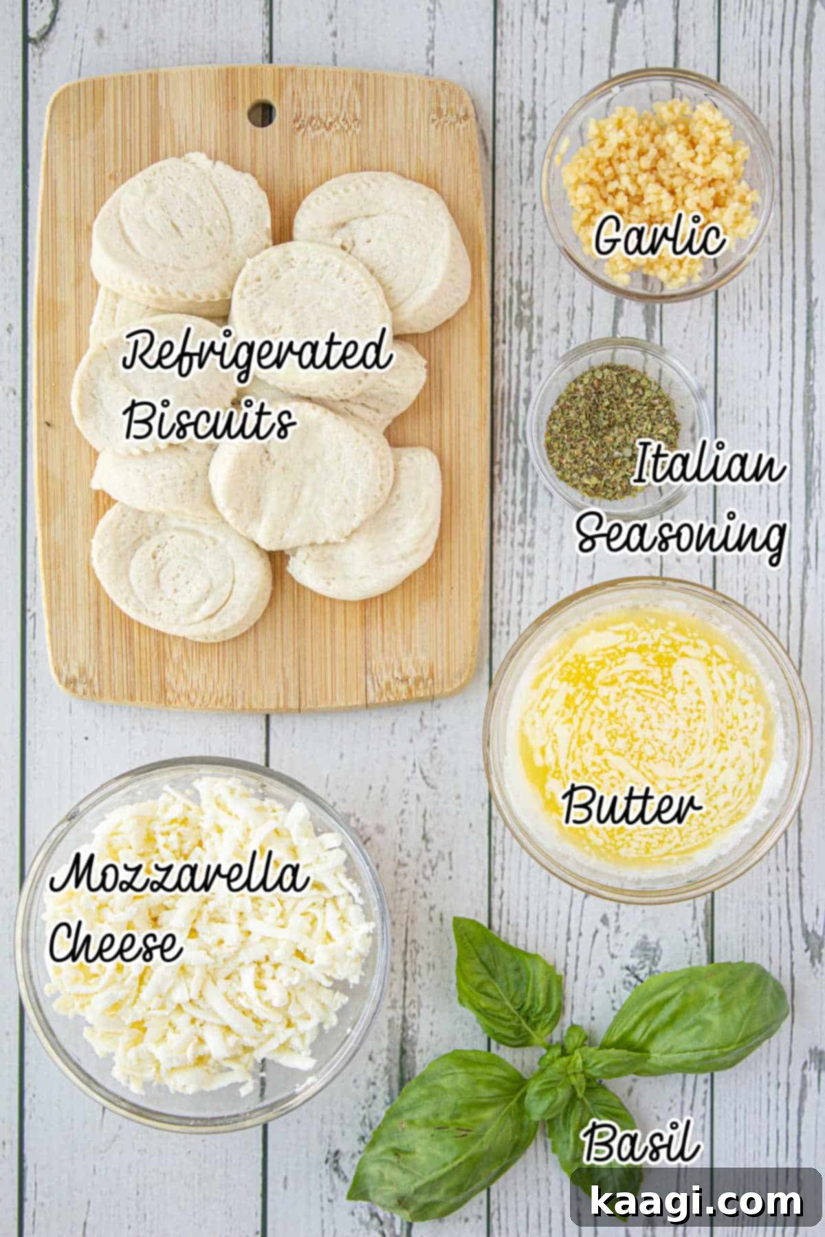 Various ingredients needed to make Italian Monkey Bread, including canned biscuits, mozzarella, butter, garlic, basil, and Italian seasoning.