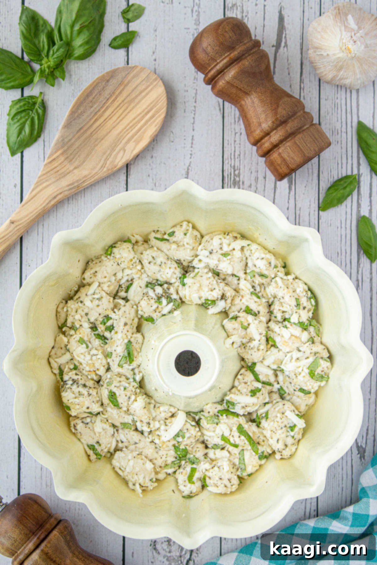 A bundt pan filled with refrigerated biscuit dough pieces, cheese, and seasonings, ready for baking.