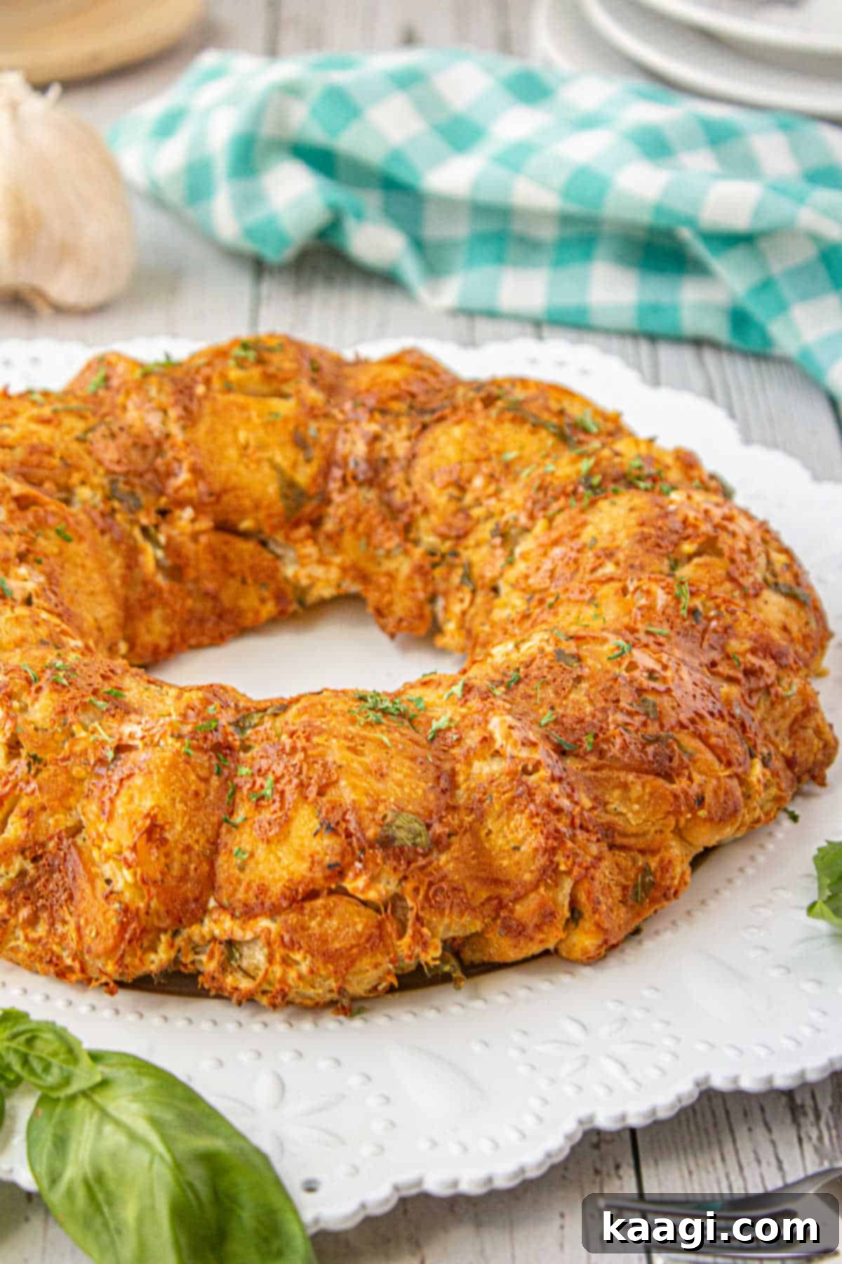 A piece of Italian monkey bread on a white plate, garnished with a fresh basil leaf.