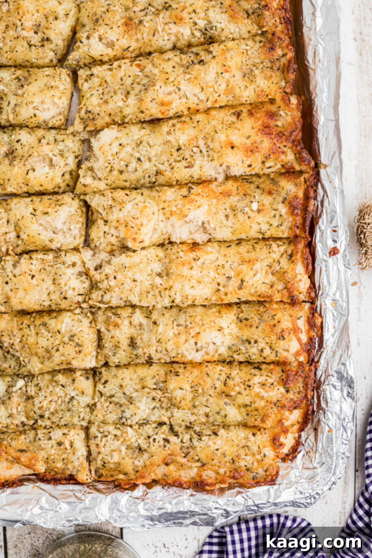 Mastering Little Caesars Cheesy Bread at Home 4 Close up view of the corner of a pan of golden brown Little Caesars Italian cheese bread, showing the melted cheese and crispy edges.