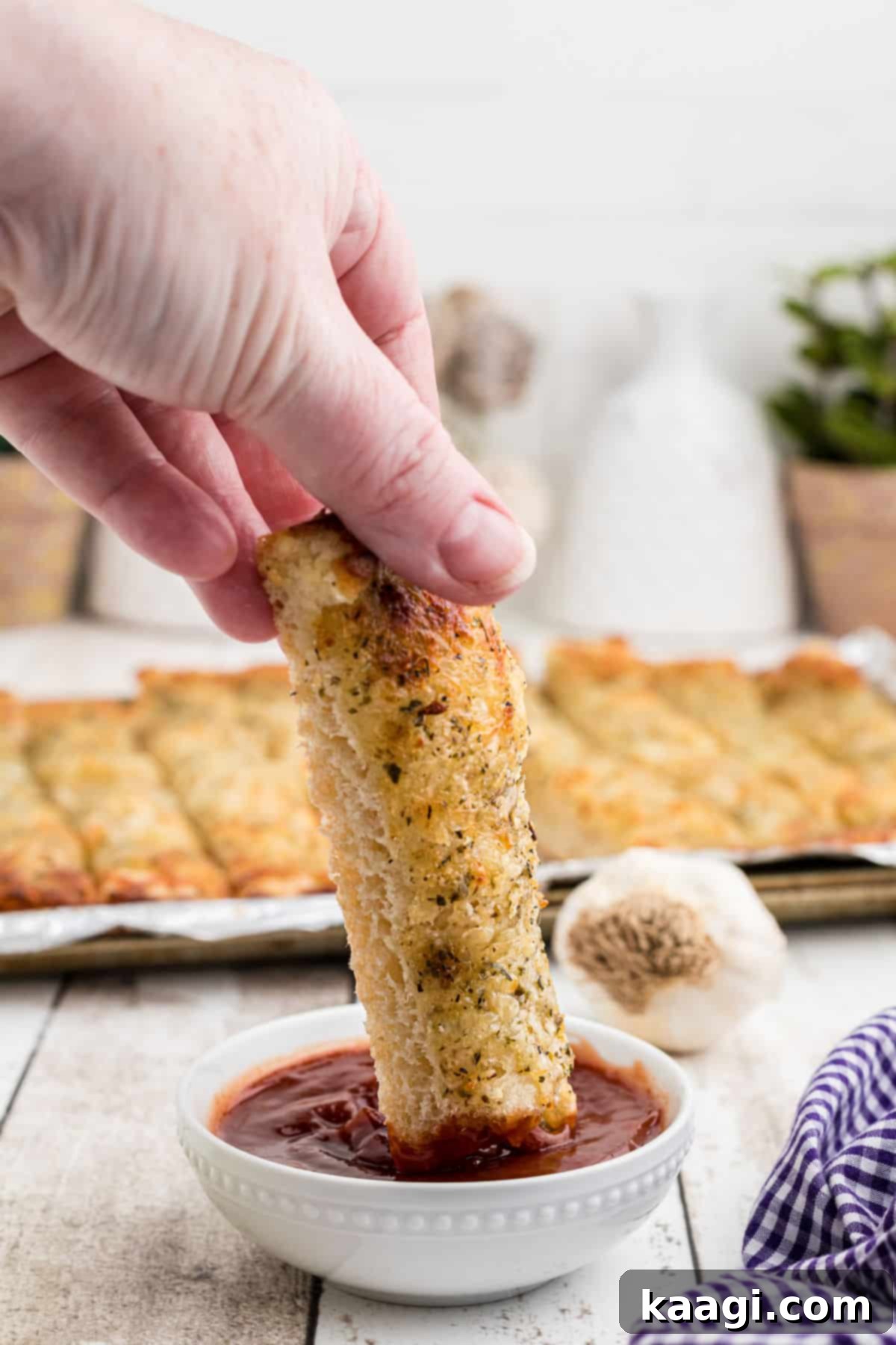 Mastering Little Caesars Cheesy Bread at Home 5 An Italian cheese bread stick being dipped into a warm marinara sauce, showing the melted cheese.