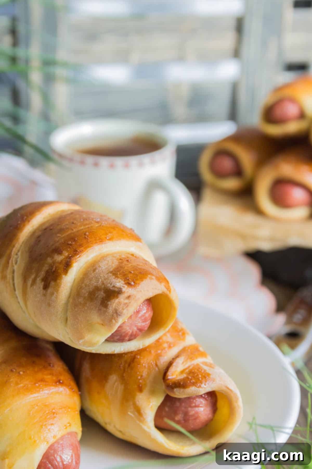 A beautiful serving dish with air-fried pigs in blankets stacked pyramid-style, garnished and ready for guests.