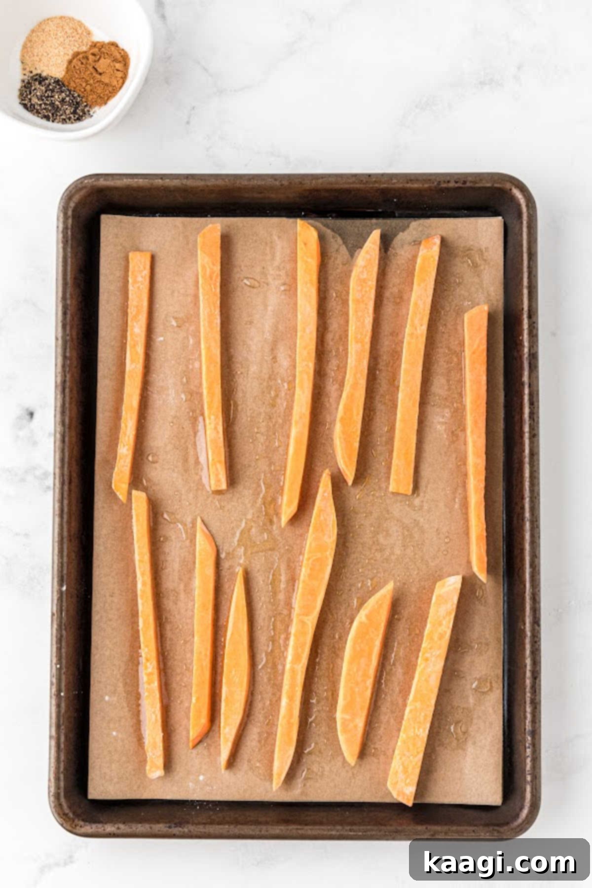 Sweet potatoes lined up on a baking sheet.