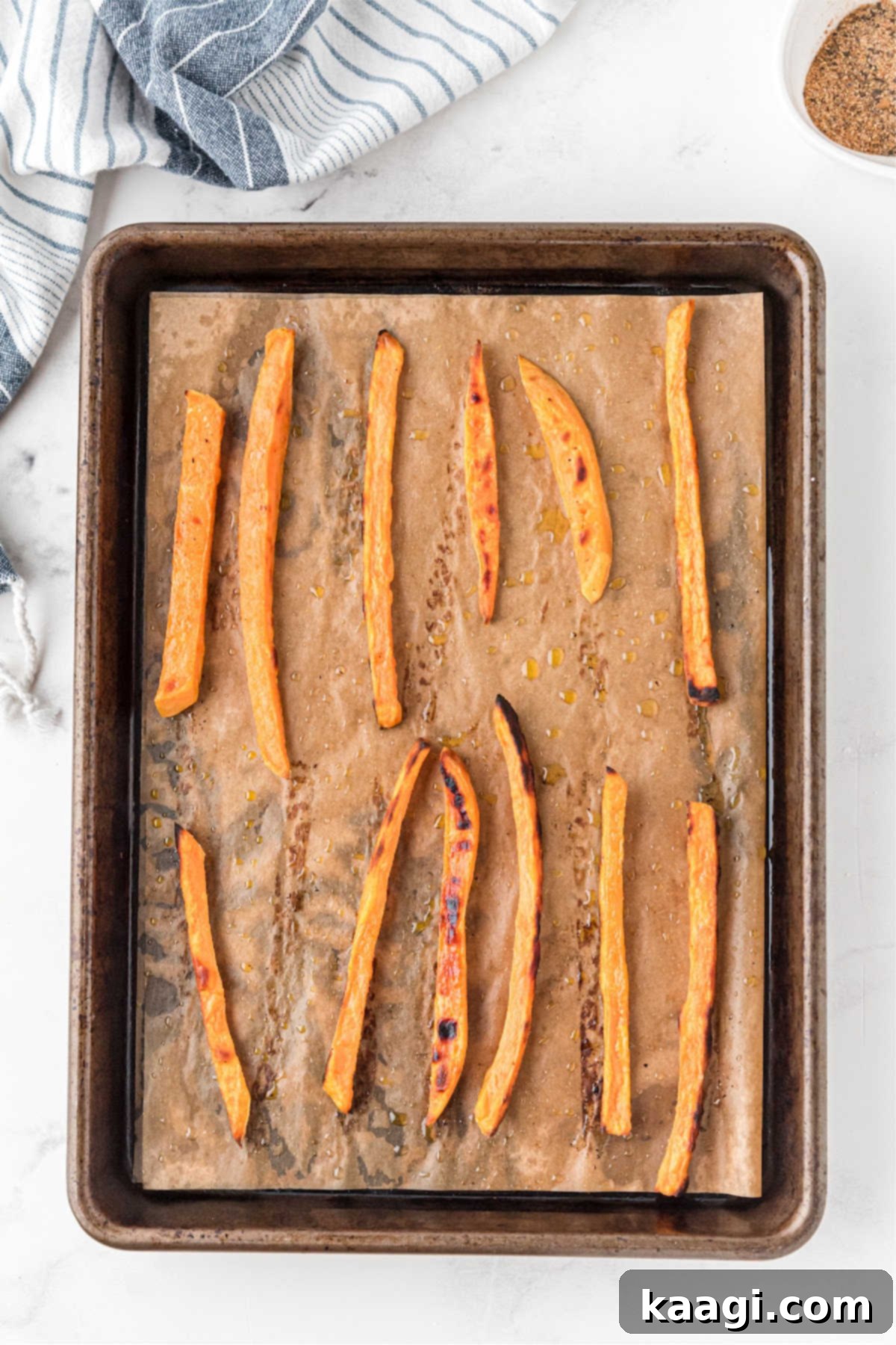 Sweet potato fries being seasoned after finished baking.