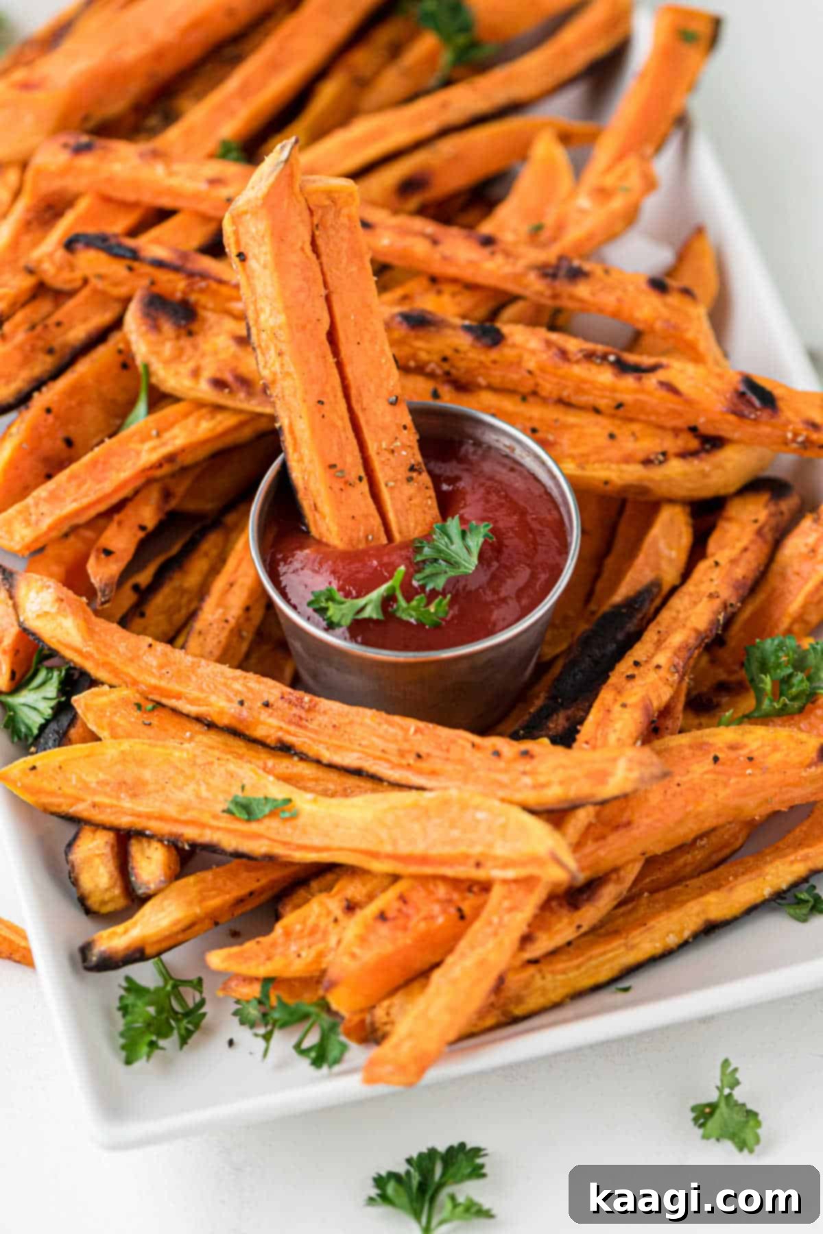 Close up of some sweet potato fries on a plate with some dipping into sweet potato dip.