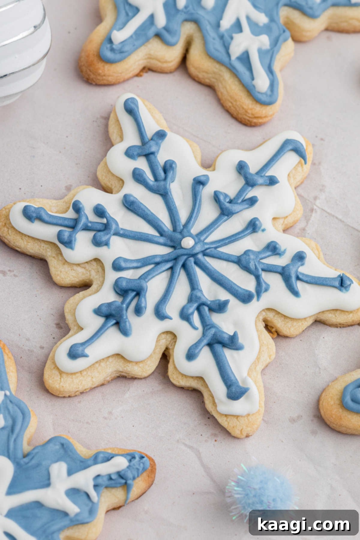 Close up of a snowflake cookie with white and blue icing.