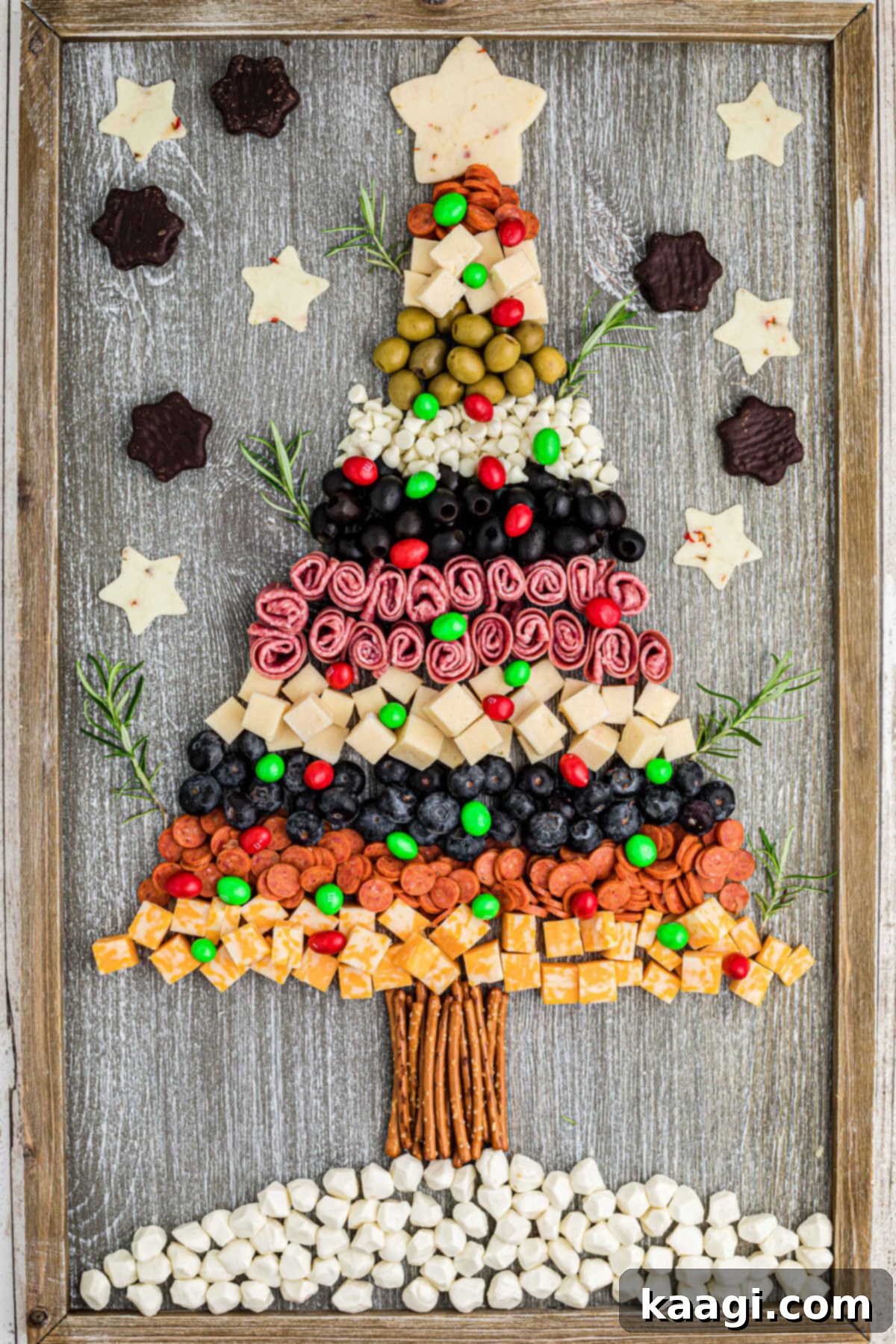 Overhead shot of a beautiful Christmas Charcuterie Board shaped like a Christmas tree, filled with various cheeses, meats, fruits, and M&Ms.