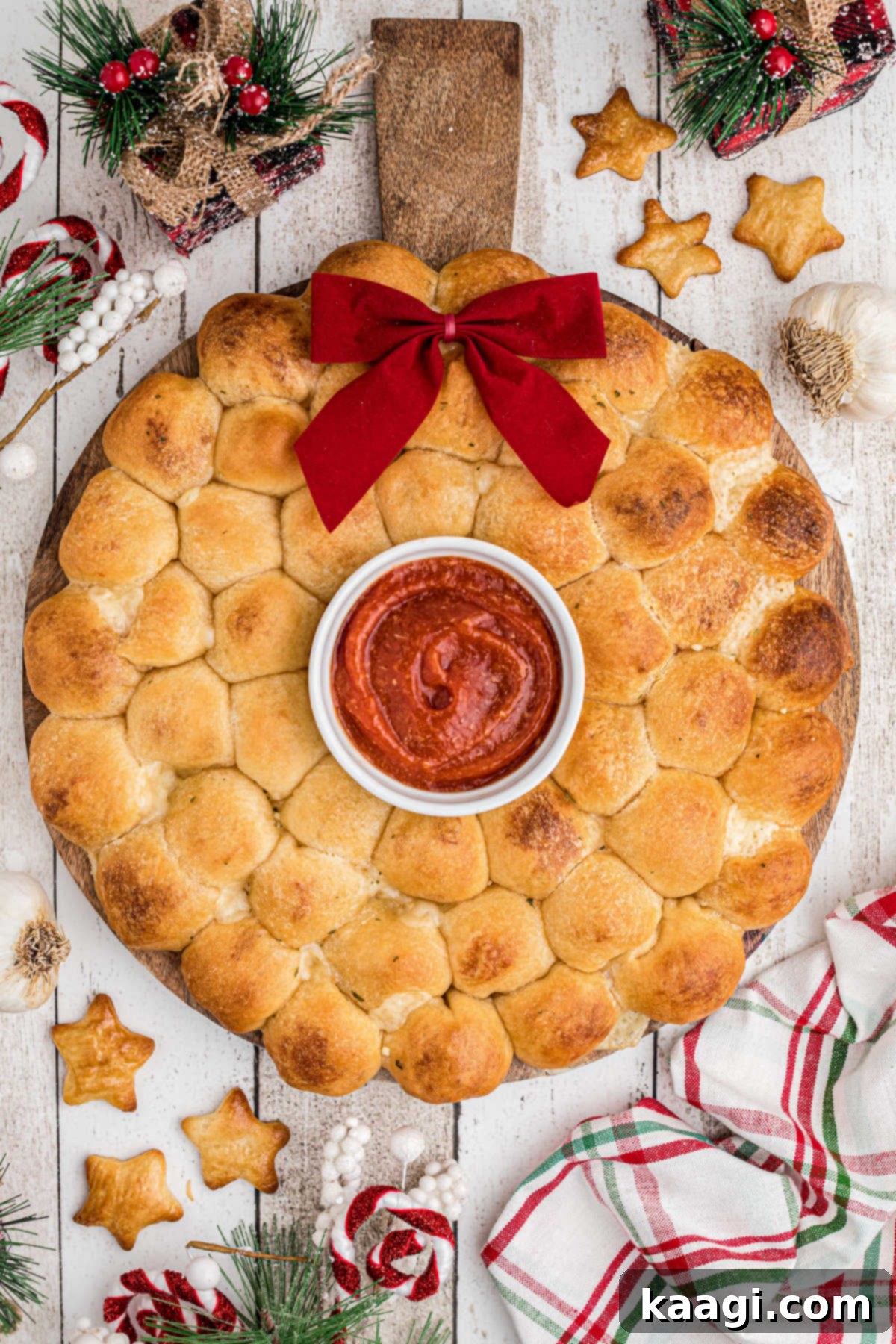 Overhead shot of a delicious Christmas pull apart bread wreath on a wooden serving board, garnished for the holidays.