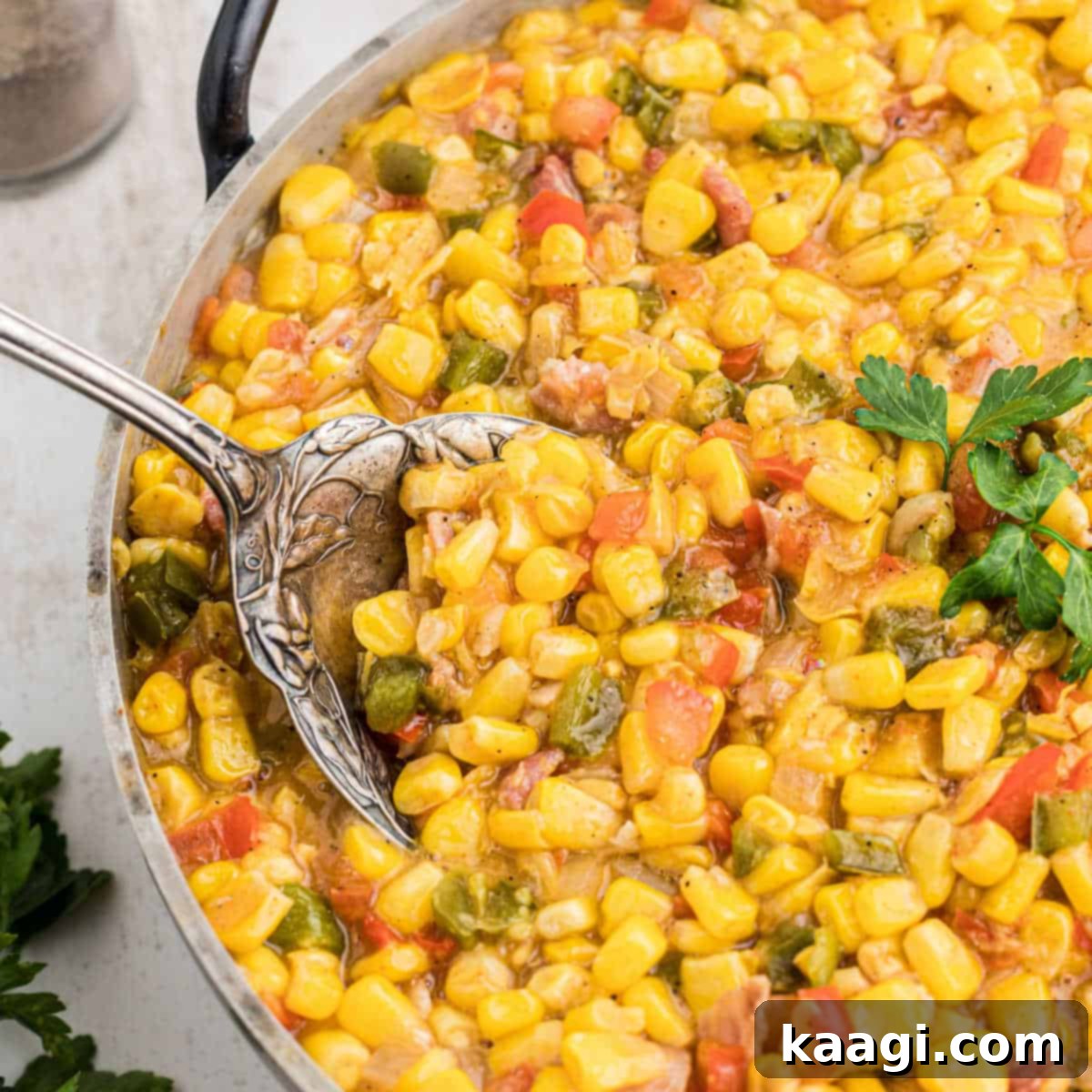 Close up of some Cajun corn maque choux with a large spoon digging in, showing its creamy texture.