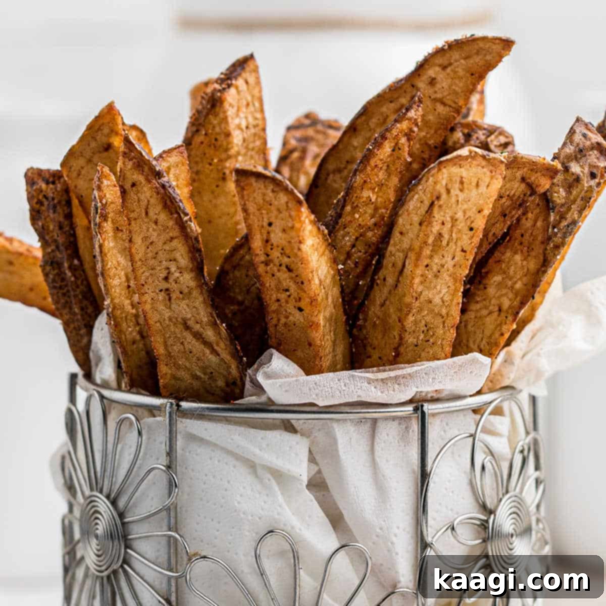 A closeup image of some perfectly seasoned Popeyes Cajun Fries in a decorative cylindrical container.