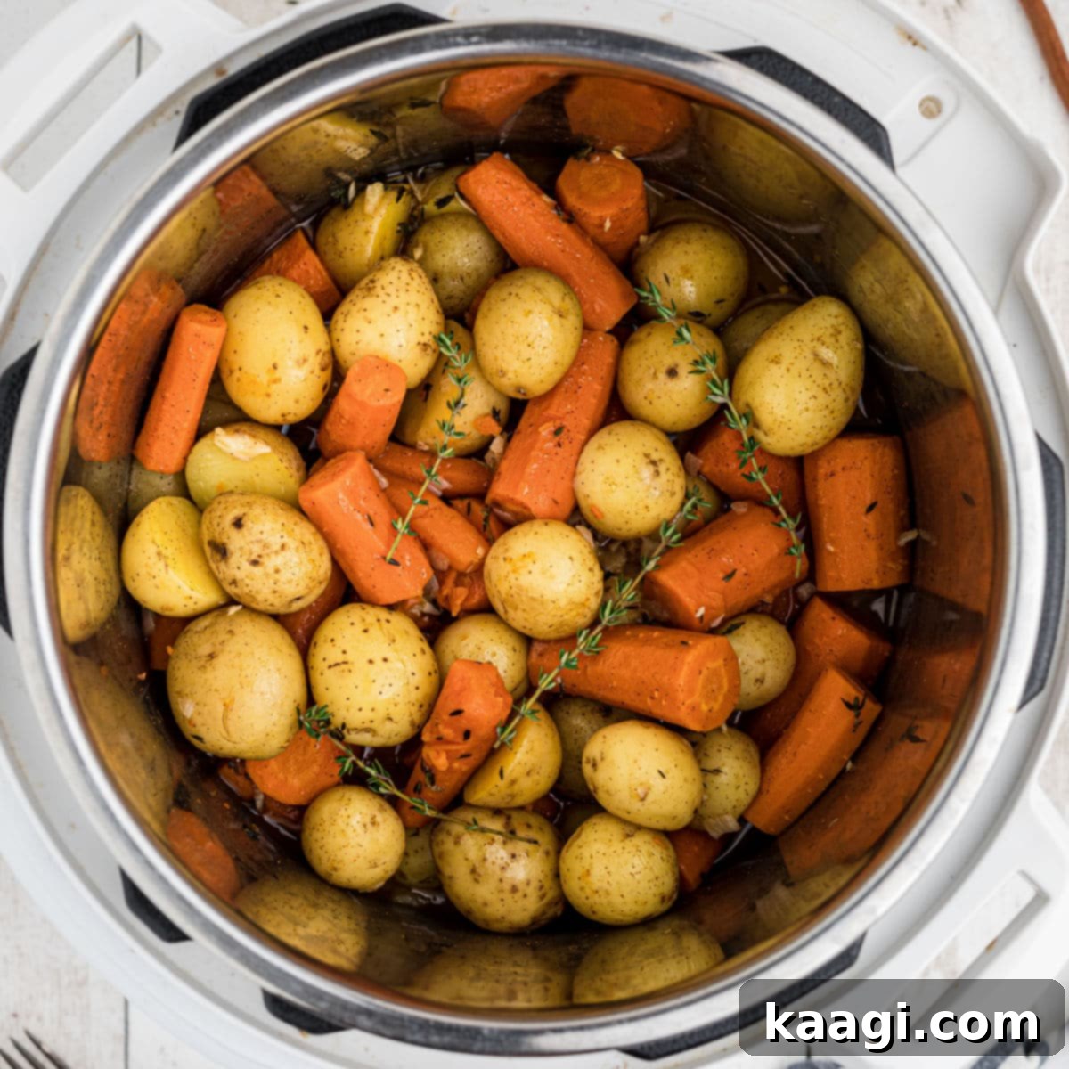 Close up overhead view of an Instant Pot filled with tender potatoes and carrots, seasoned and ready.