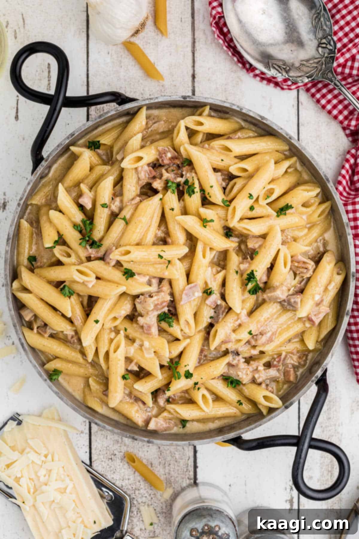 A serving spoon resting in a Dutch oven filled with creamy one pot turkey pasta, garnished with a sprinkle of fresh cheese.