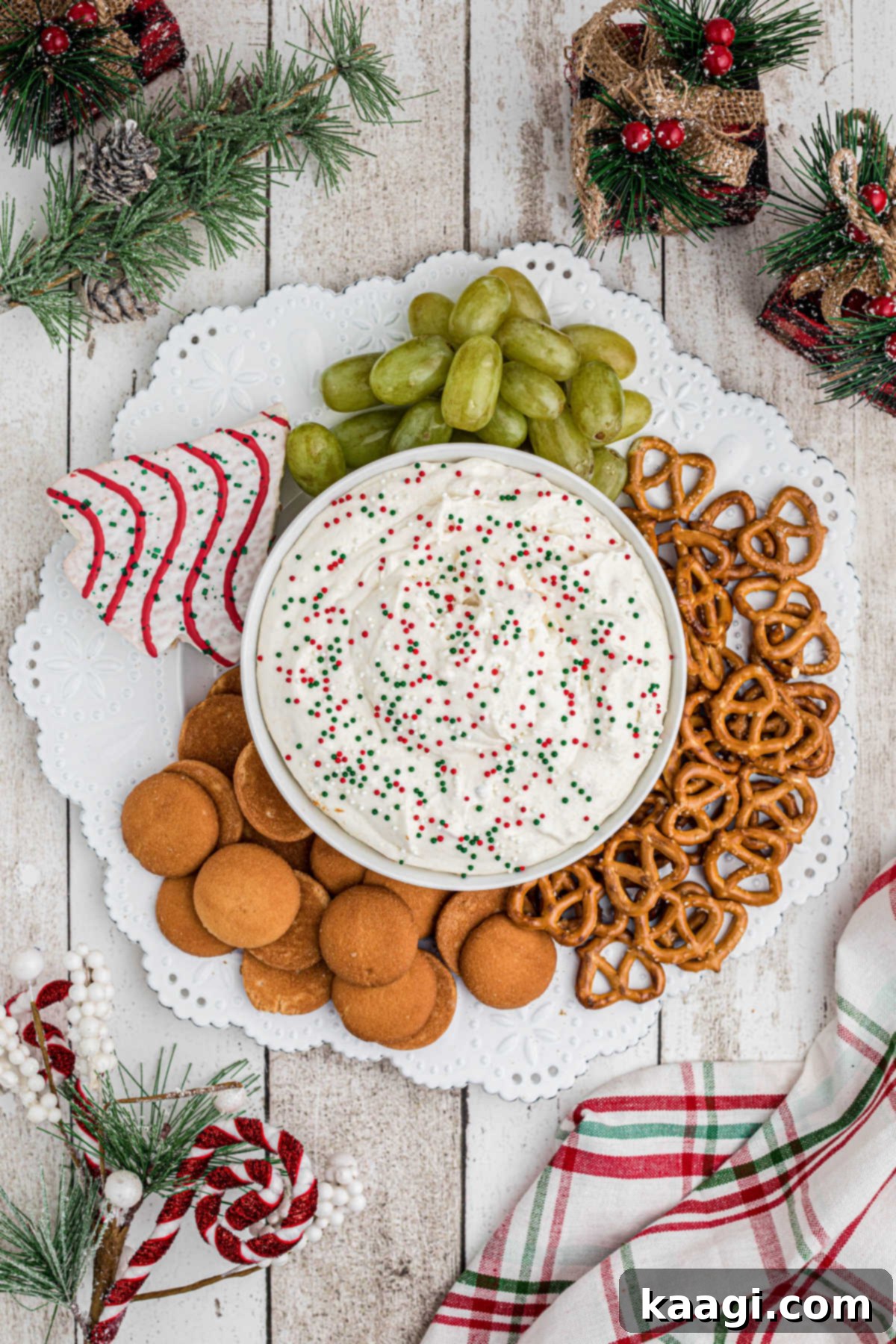 Sparkling Christmas Tree Dip 8 Overhead shot of a plate, with a bowl of Christmas Tree Dip as the centerpiece, surrounded by various cookies and fresh fruit for dipping.