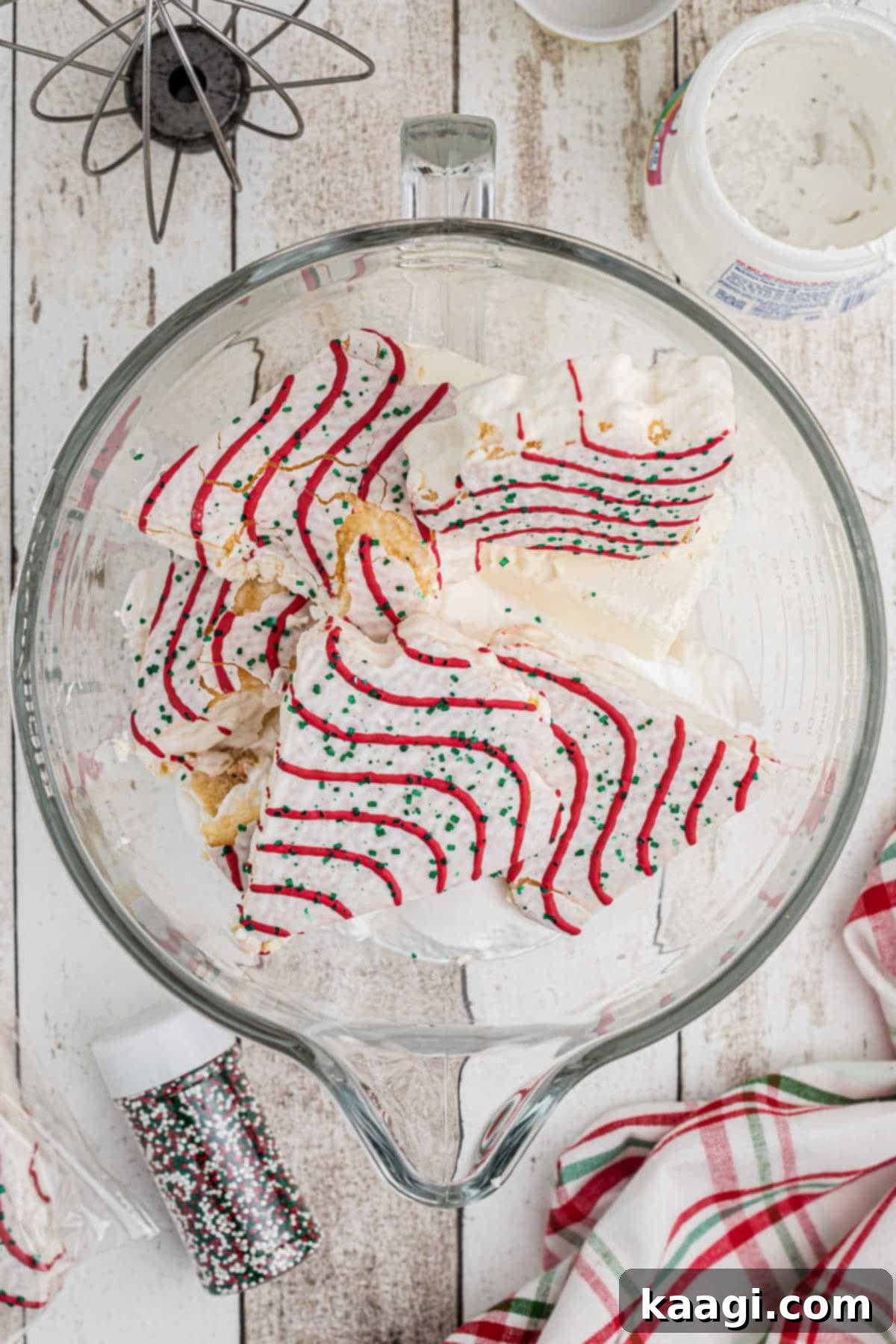 Sparkling Christmas Tree Dip 4 Ingredients including Little Debbie Christmas Trees, cream cheese, milk, whipped topping, and marshmallow creme, combined in a stand mixer bowl, ready for mixing to make Christmas Tree Dip.