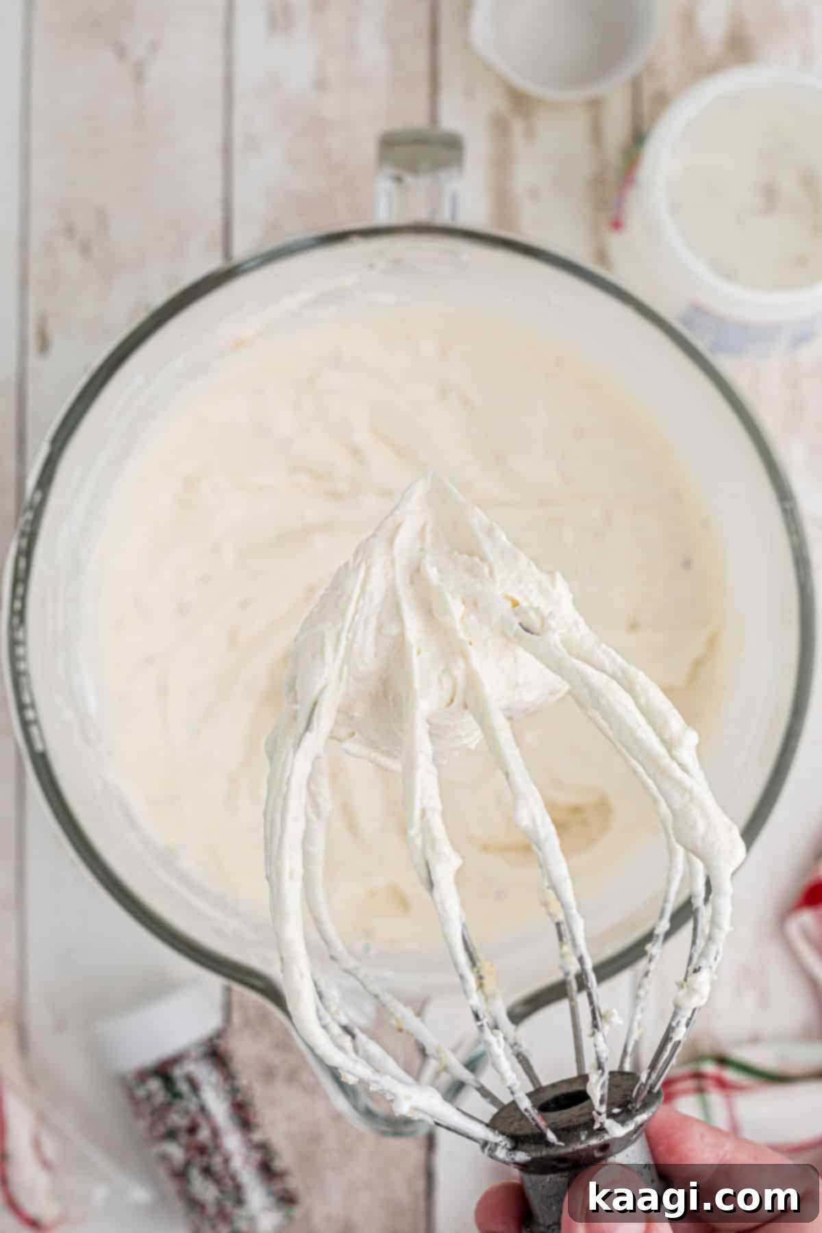 Sparkling Christmas Tree Dip 5 Close up of a wire whisk attachment in a stand mixer, with the creamy, light green Christmas Tree Dip fully mixed.