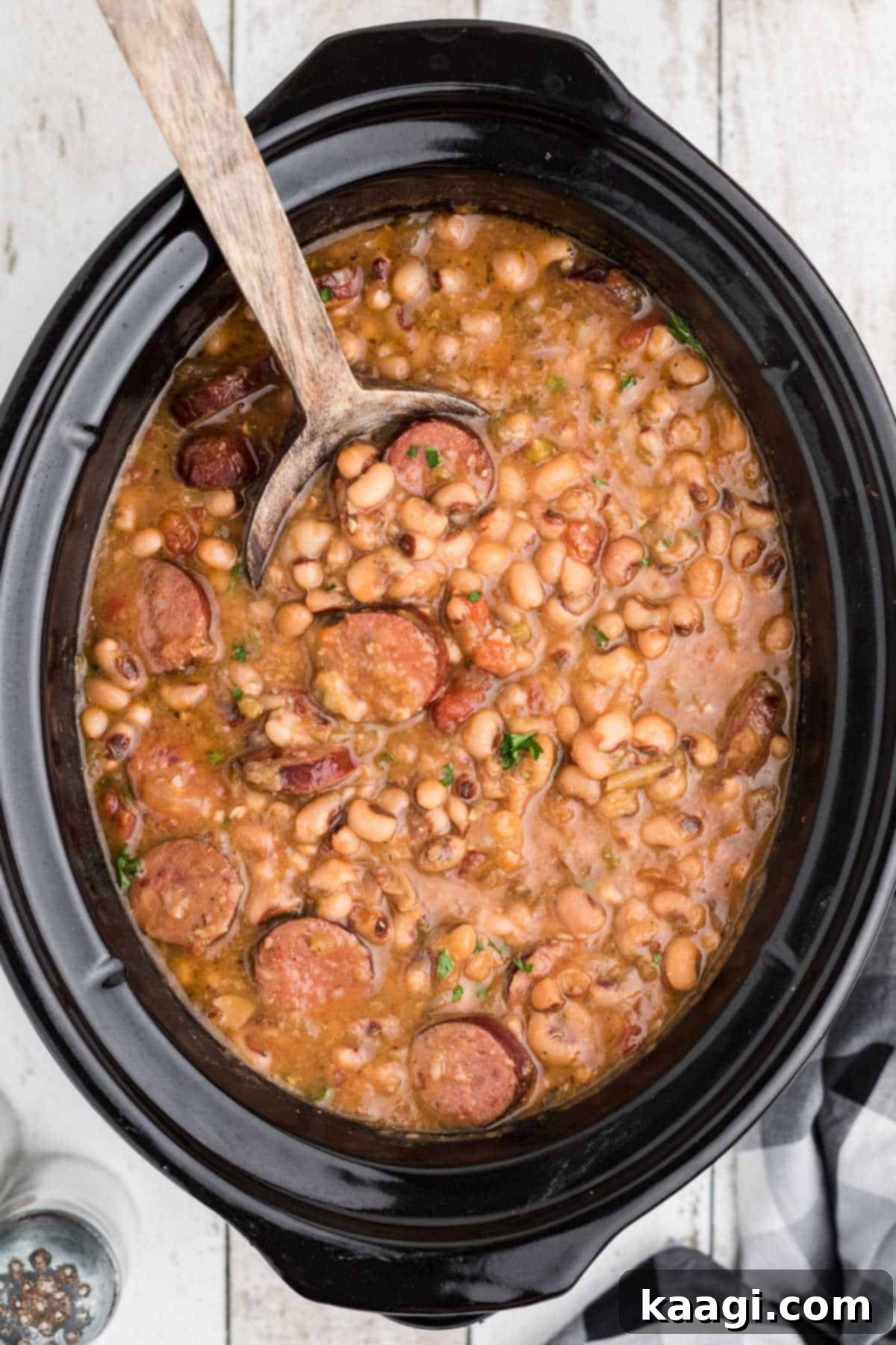 Easy Slow Cooker Hoppin John 2 Close up shot of a steaming bowl of Crock Pot Hoppin' John with a spoon, highlighting the rich texture of black-eyed peas and smoked sausage.