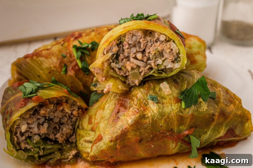 cabbage rolls in pile with one sliced open showing the stuffed meat inside