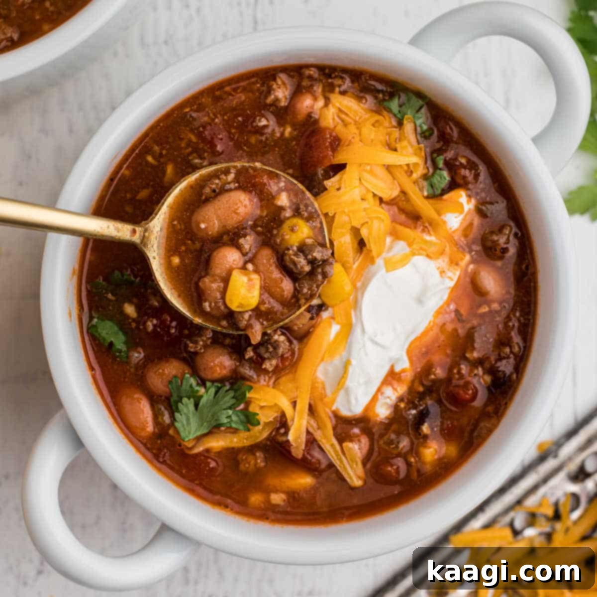 bowl of taco soup with grated cheese and sour cream with a spoon digging in