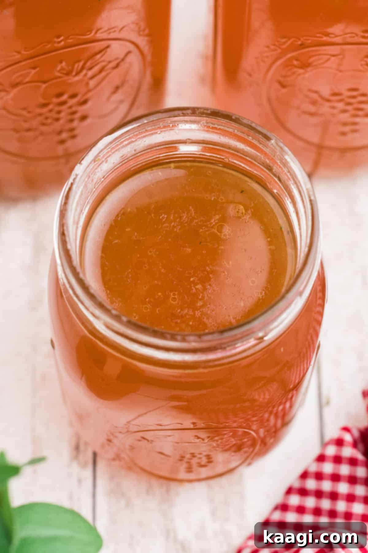 Overhead shot of an open mason jar of Rotisserie Chicken Bone Broth, showcasing its rich golden color.