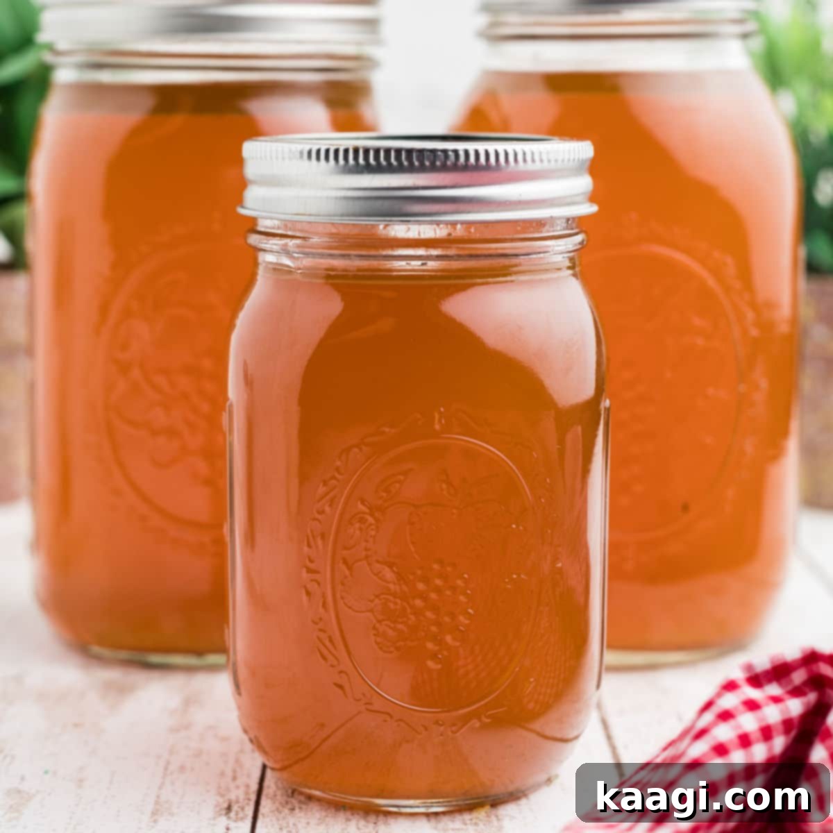 Three mason jars filled with golden Rotisserie Chicken Bone Broth, neatly lined up, showing the broth's inviting color and clarity.