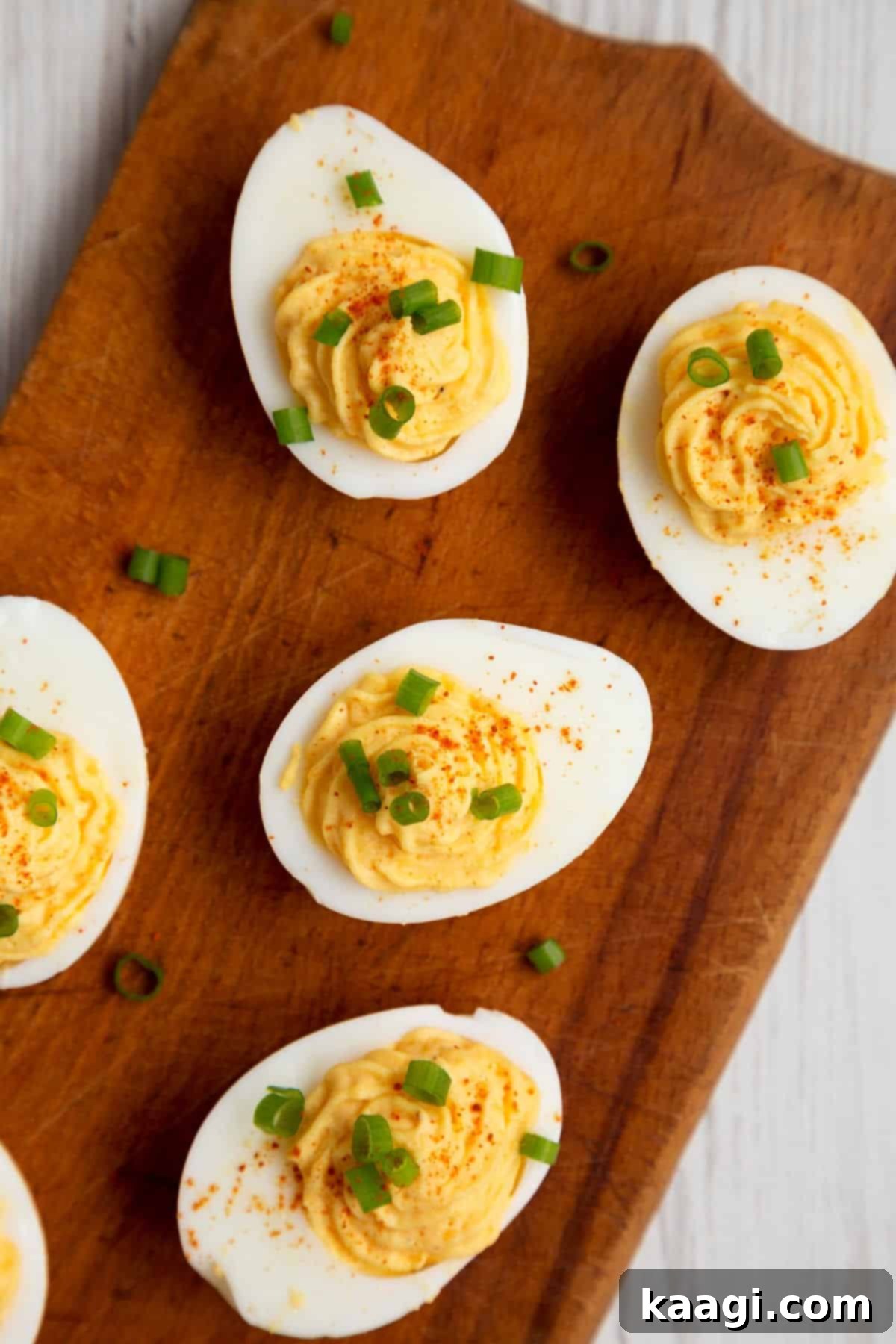 Second Life for Deviled Eggs 8 A beautiful wooden board displaying freshly made deviled eggs, garnished with finely chopped green onions, ready for serving.