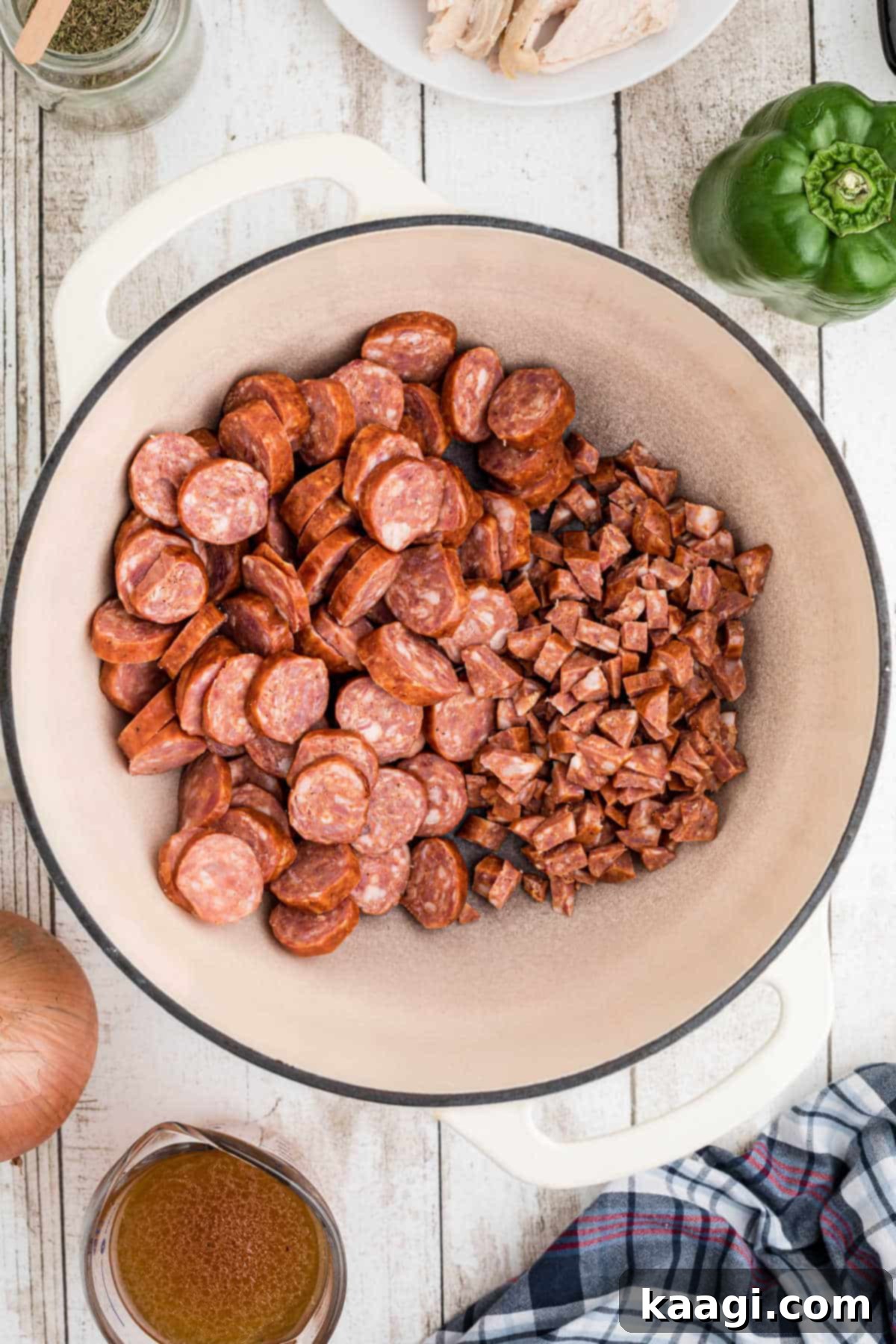 Chopped smoked sausages searing in a large Dutch Oven, developing a rich brown crust.