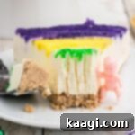 Festive Mardi Gras Cheesecake 7 Close up of a slice of Mardi Gras cheesecake with a king cake baby on the side.