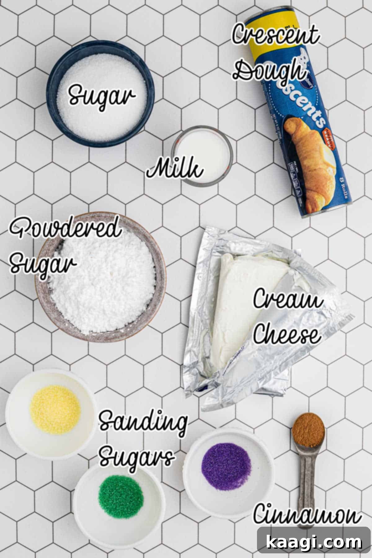 An overhead shot showcasing all the fresh ingredients perfectly arranged for making King Cake Bites, including crescent roll dough, cream cheese, sugars, cinnamon, milk, and Mardi Gras colored sanding sugars.