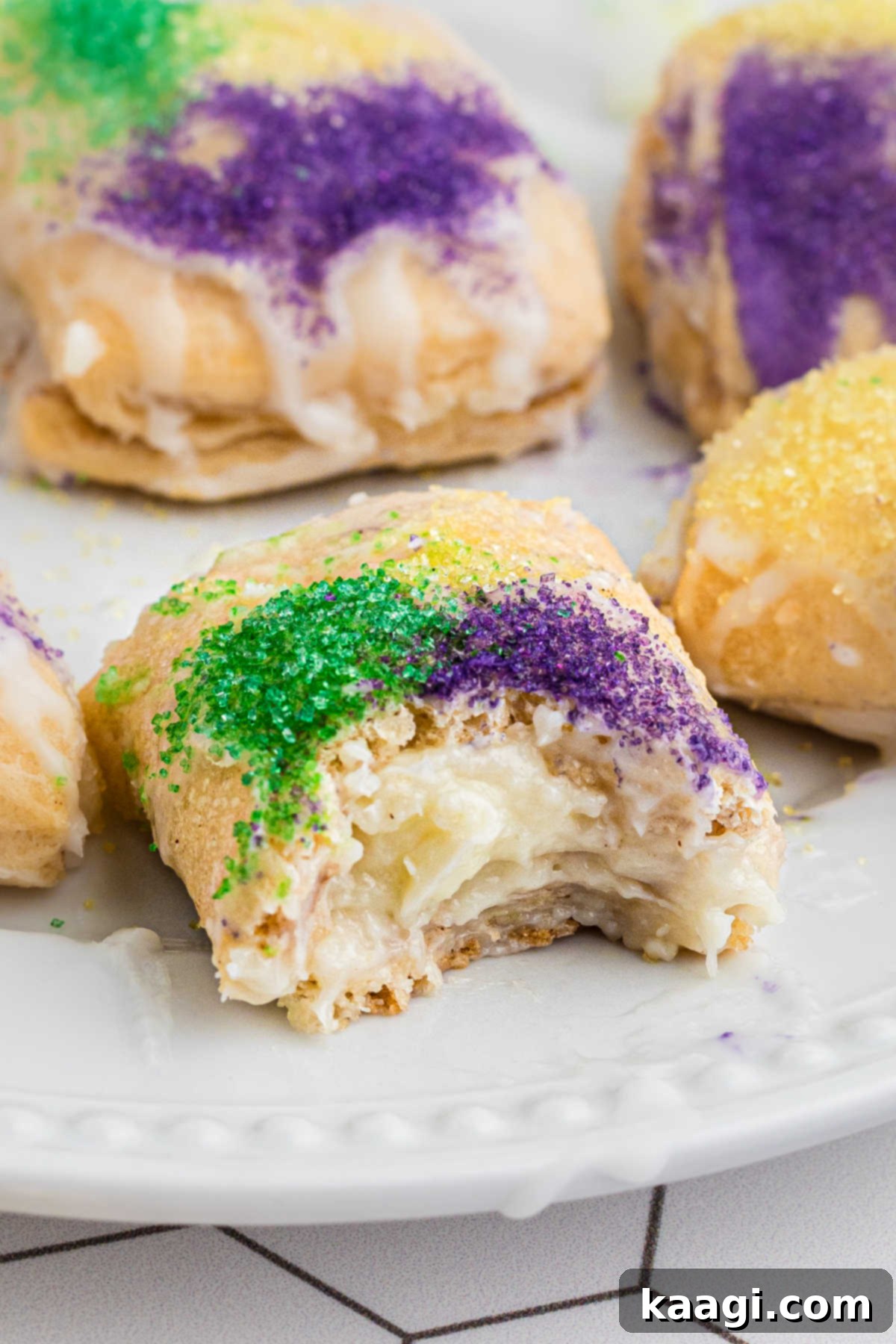 A close-up photo of a single King Cake Bite with a bite taken out, revealing the creamy cinnamon filling and flaky pastry texture.