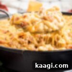 Very close up shot of a spoon lifting out some crawfish mac and cheese from a skillet.