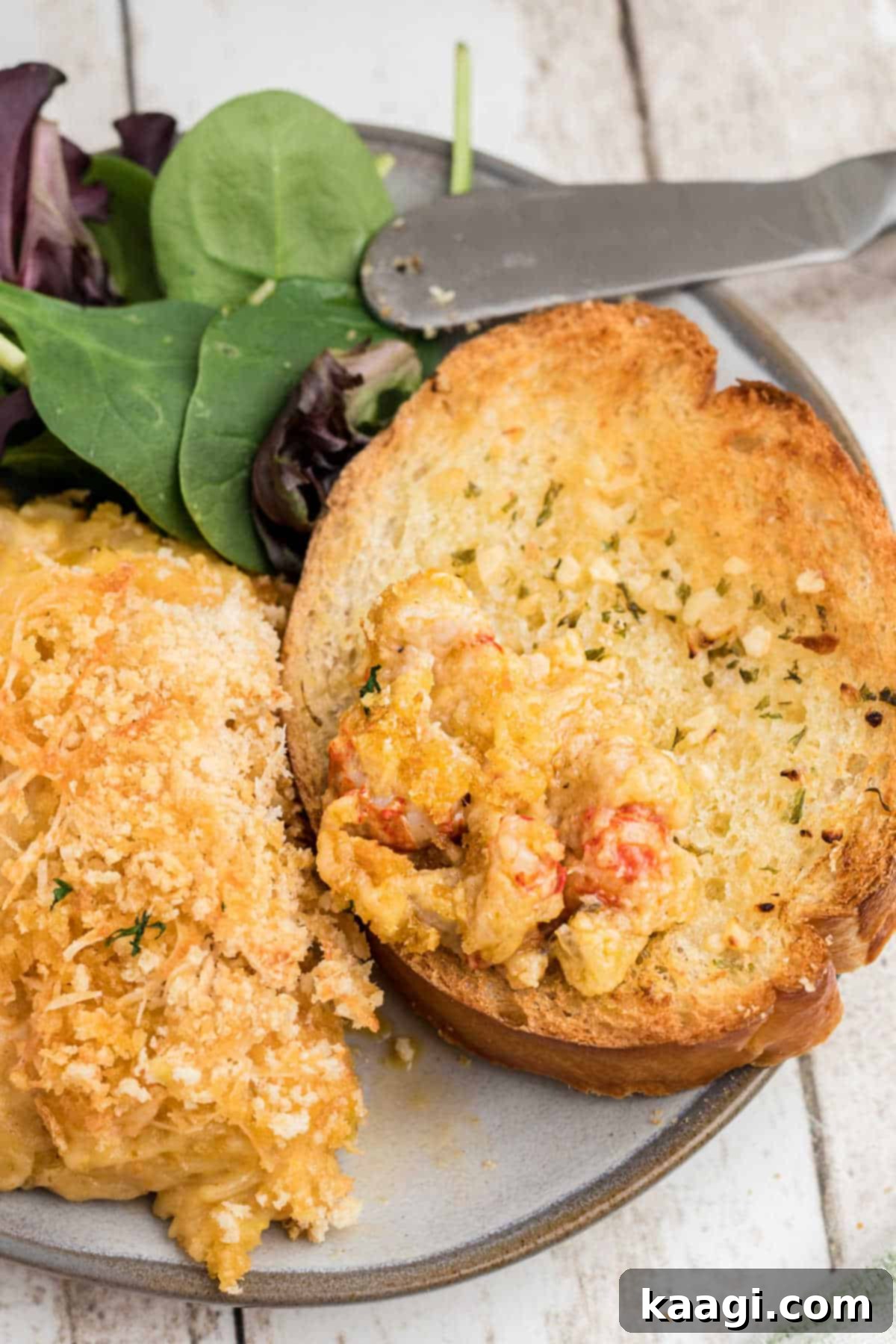 Close up of a piece of garlic toast with a generous dollop of crawfish au gratin, garnished with fresh parsley.