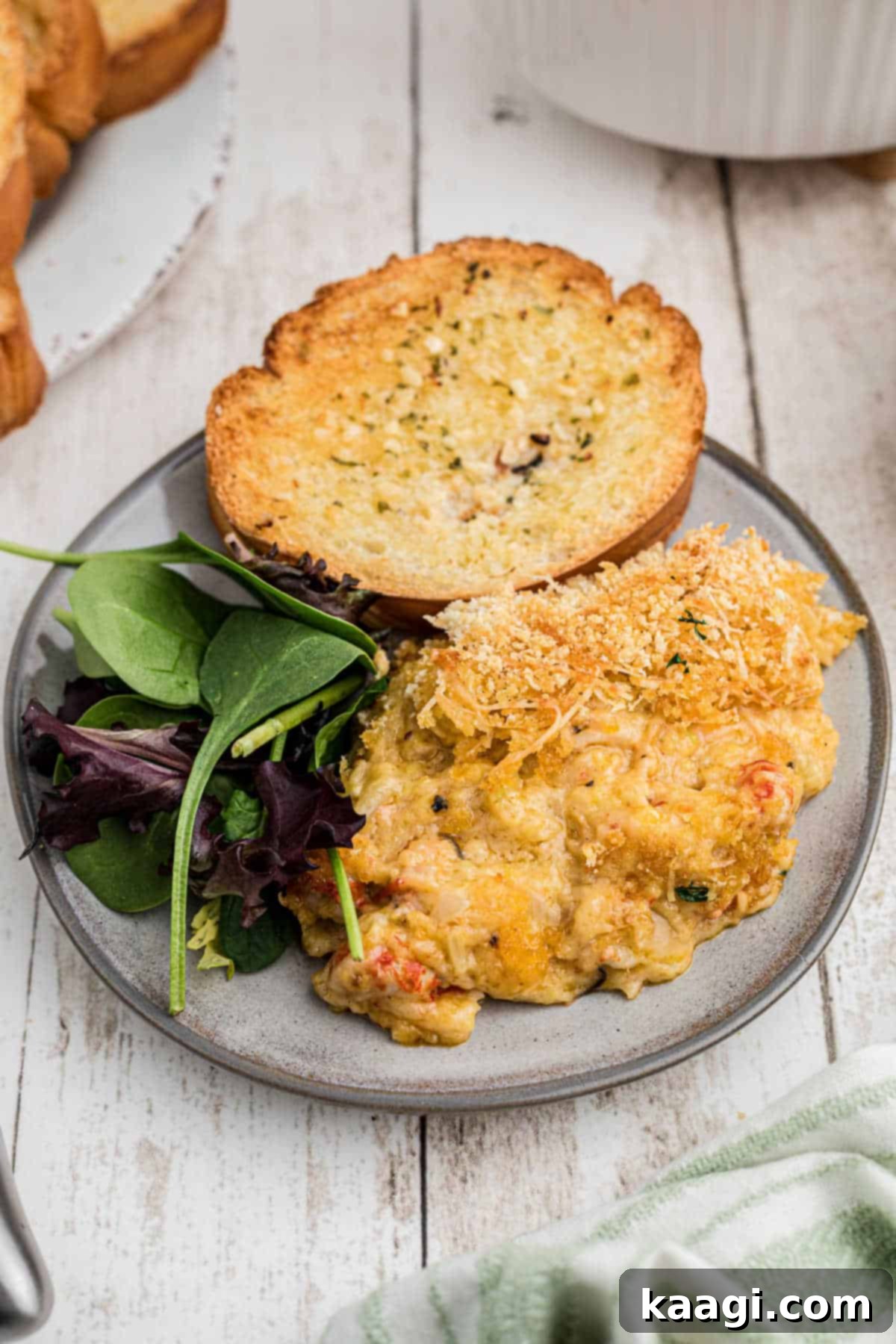 A plate with a scoop of crawfish au gratin and a piece of garlic toast, ready to be enjoyed.