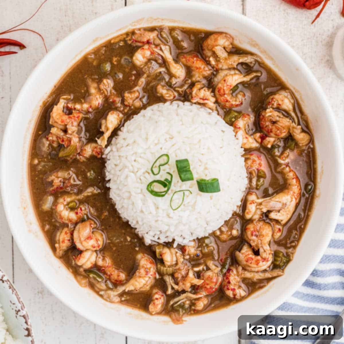 An overhead shot of a steaming bowl of authentic Crawfish Stew, served with a mound of fluffy white rice.