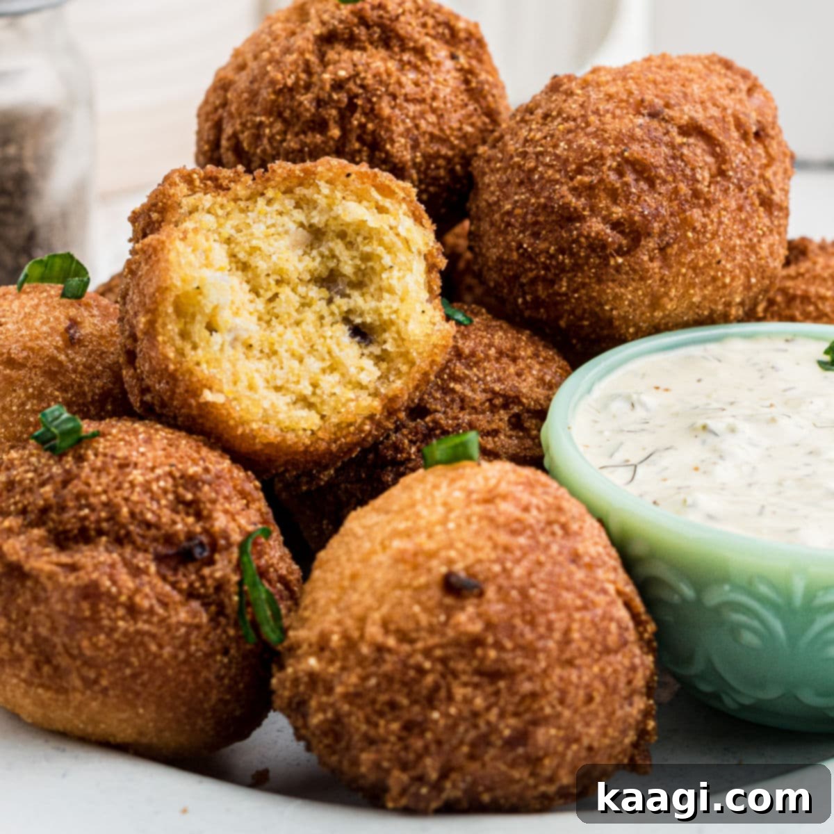 A plate of golden Southern Sweet Hush Puppies, with one broken open to show its tender interior.