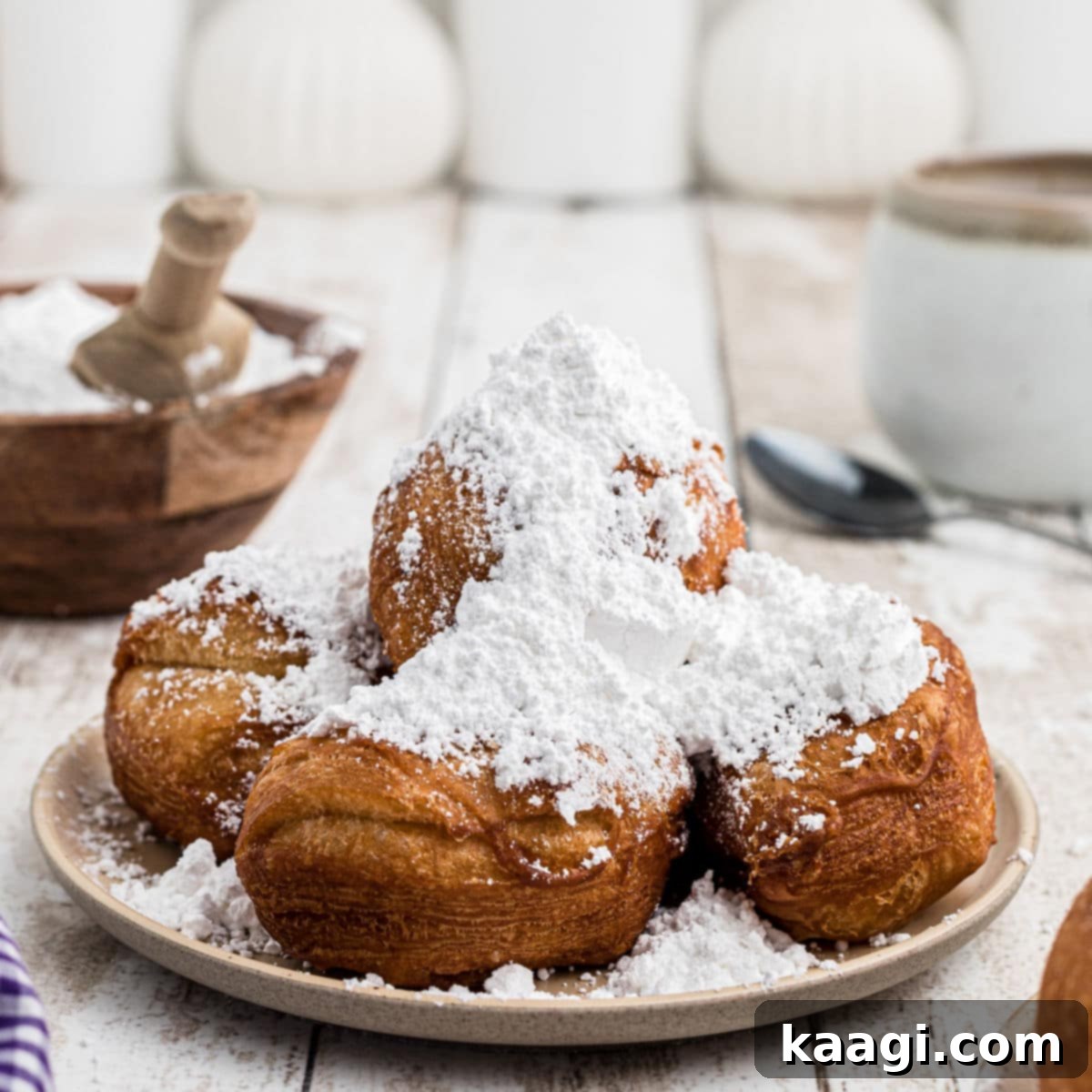 A plate piled high with golden Biscuit Beignets, generously dusted with powdered sugar.