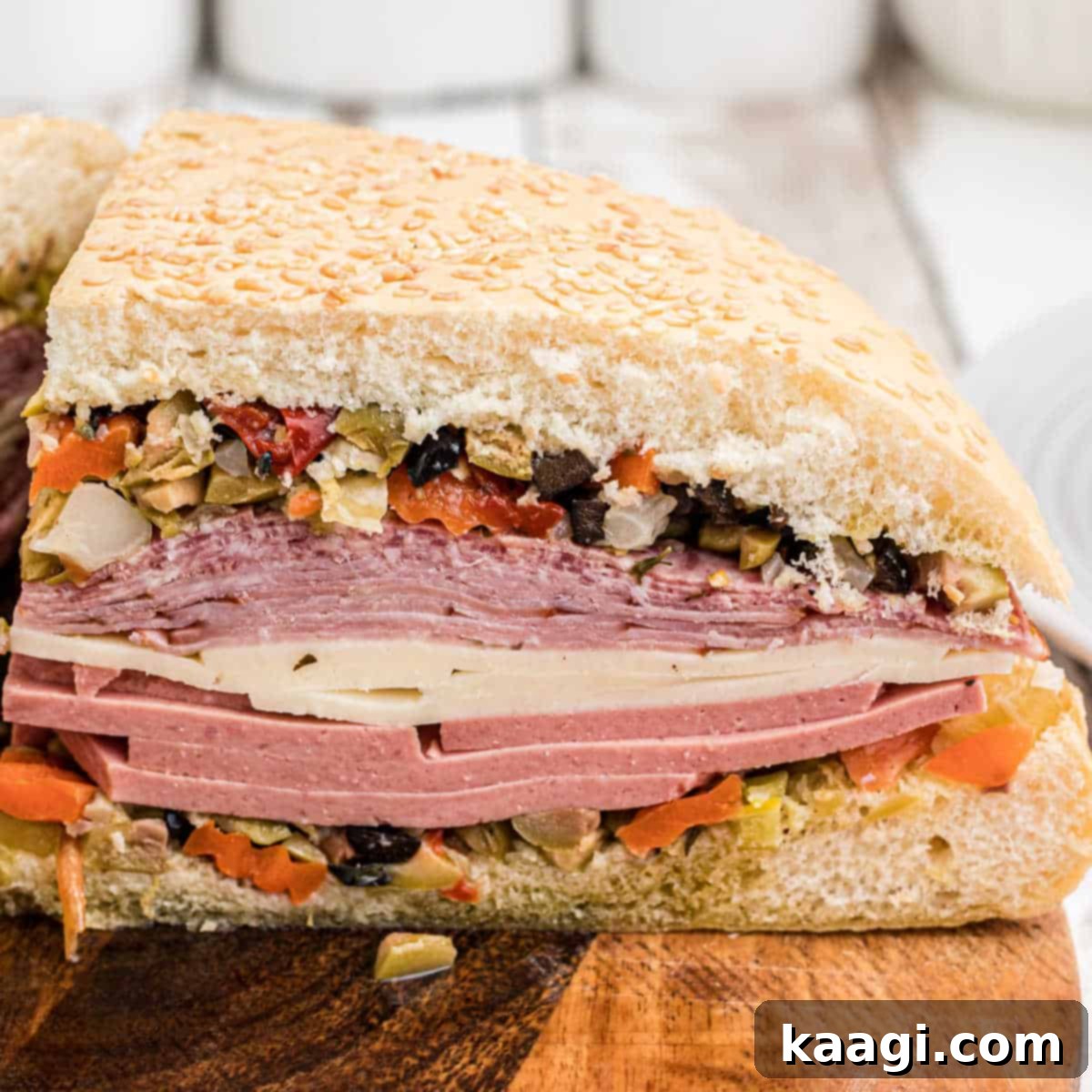 A close-up of a generously filled Cajun Muffuletta Sandwich, showcasing layers of meats, cheeses, and olive salad.